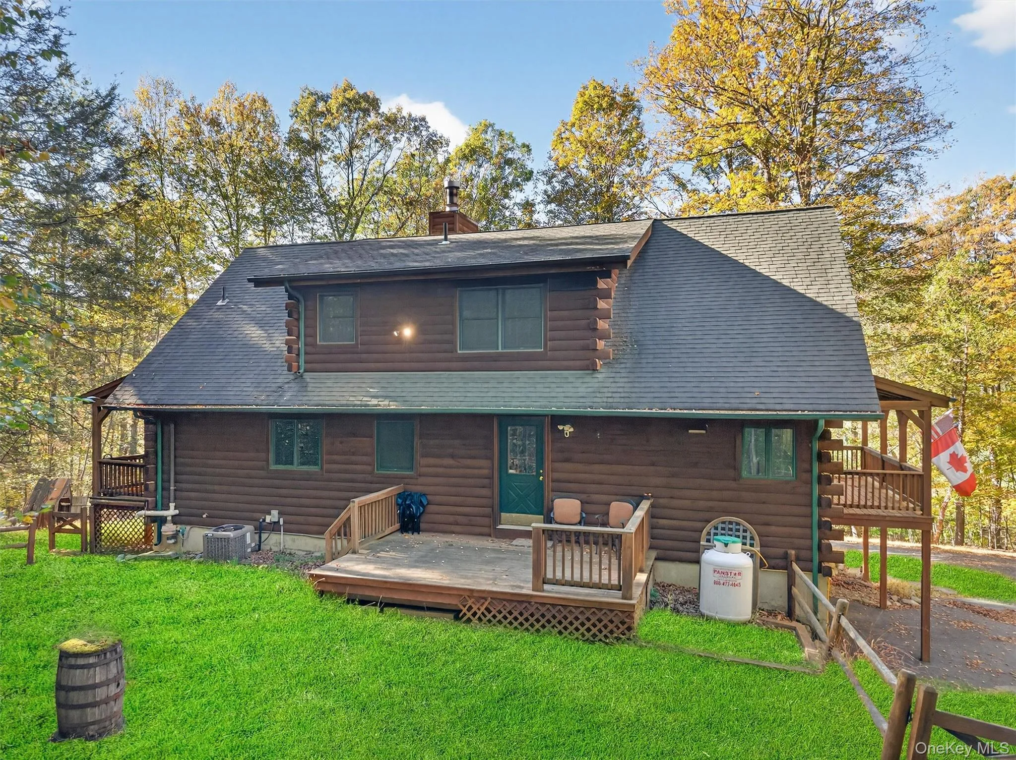 Back of property with a deck, a yard, and a shingled roof Back of property with a deck, a yard, and a shingled roof