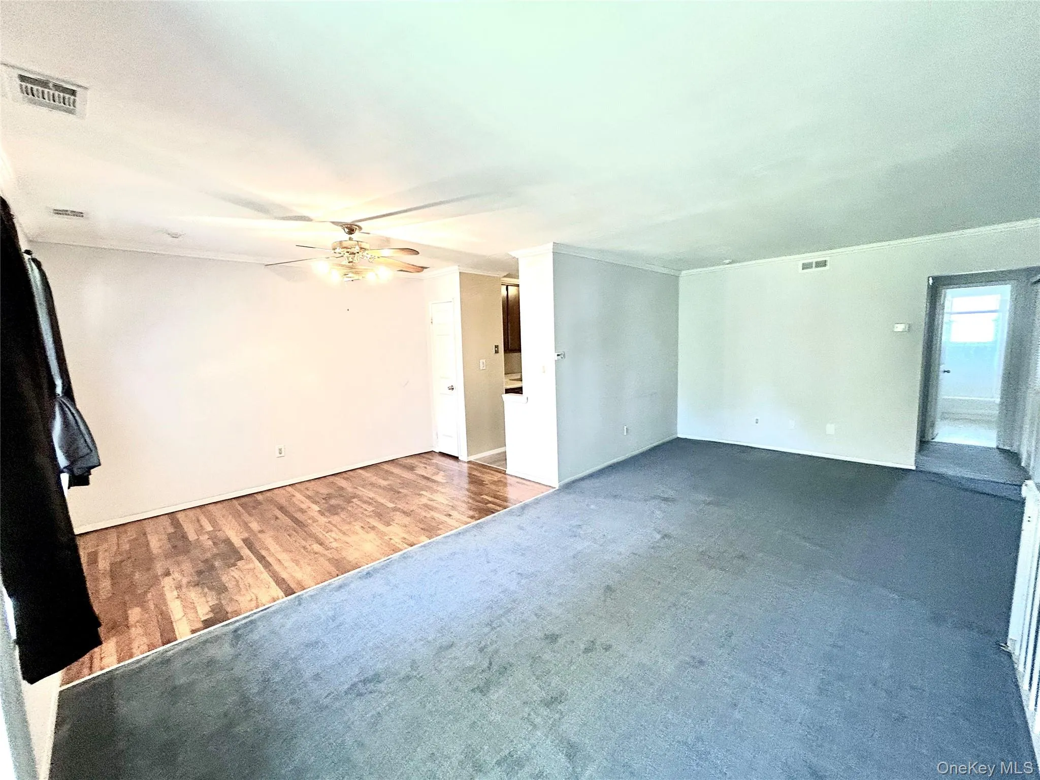 Unfurnished living room featuring carpet flooring, crown molding, wood finished floors, and a ceiling fan Unfurnished living room featuring carpet flooring, crown molding, wood finished floors, and a ceiling fan