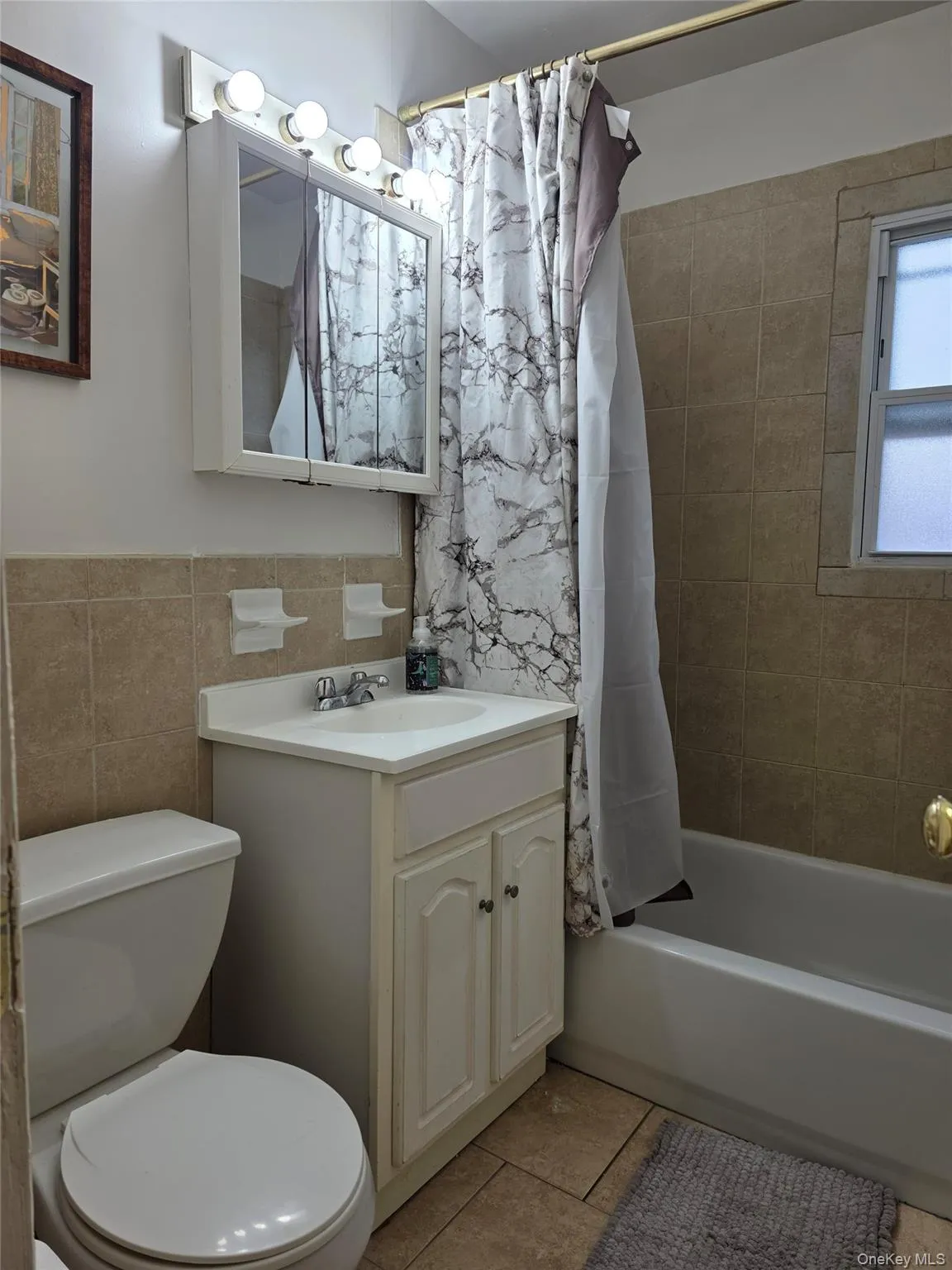 Bathroom with vanity, tile walls, light tile patterned floors, and shower / tub combo with curtain Bathroom with vanity, tile walls, light tile patterned floors, and shower / tub combo with curtain