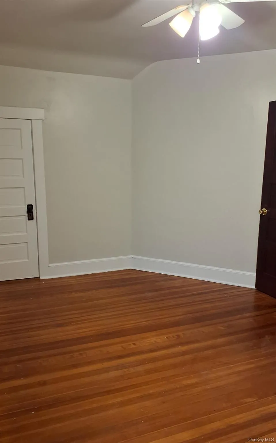 Empty room featuring dark wood finished floors and ceiling fan Empty room featuring dark wood finished floors and ceiling fan