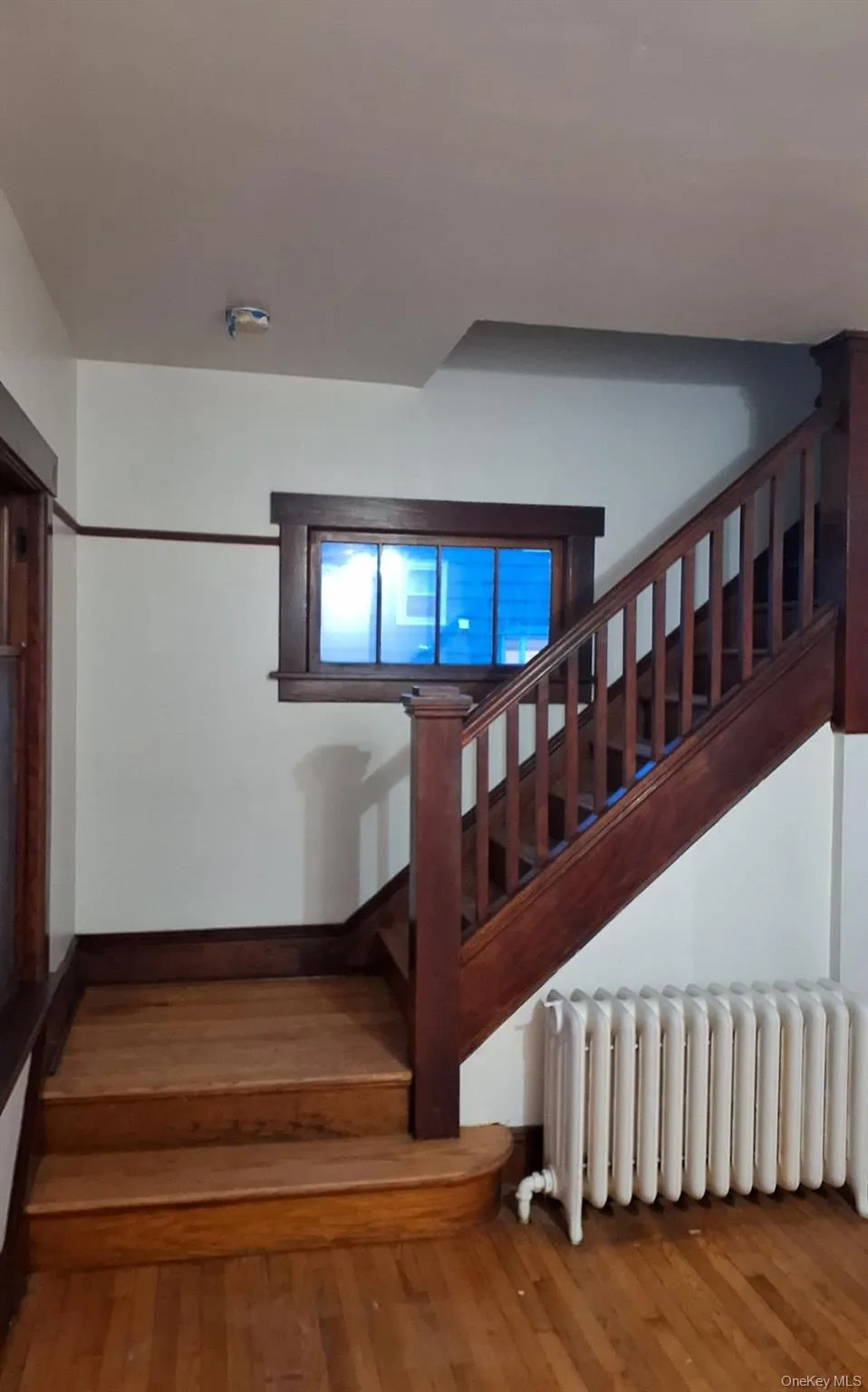 Stairway featuring radiator and hardwood / wood-style floors Stairway featuring radiator and hardwood / wood-style floors