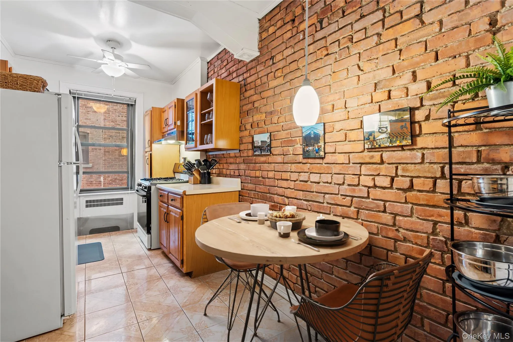 Kitchen with freestanding refrigerator, light countertops, brown cabinets, crown molding, and range with gas stovetop Kitchen with freestanding refrigerator, light countertops, brown cabinets, crown molding, and range with gas stovetop