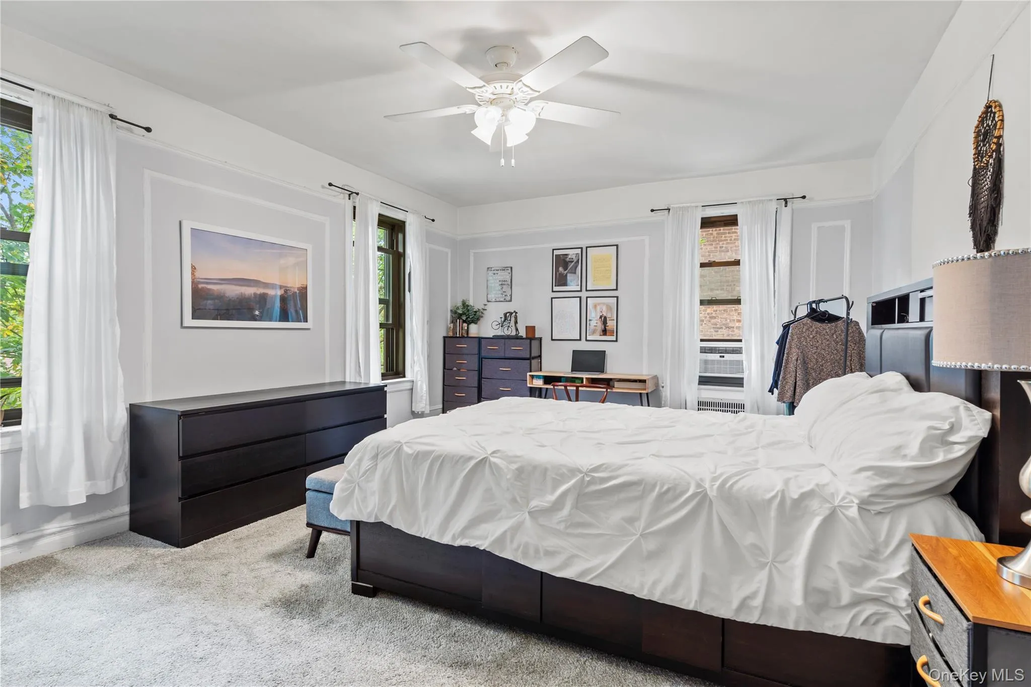 Carpeted bedroom featuring multiple windows and a ceiling fan Carpeted bedroom featuring multiple windows and a ceiling fan
