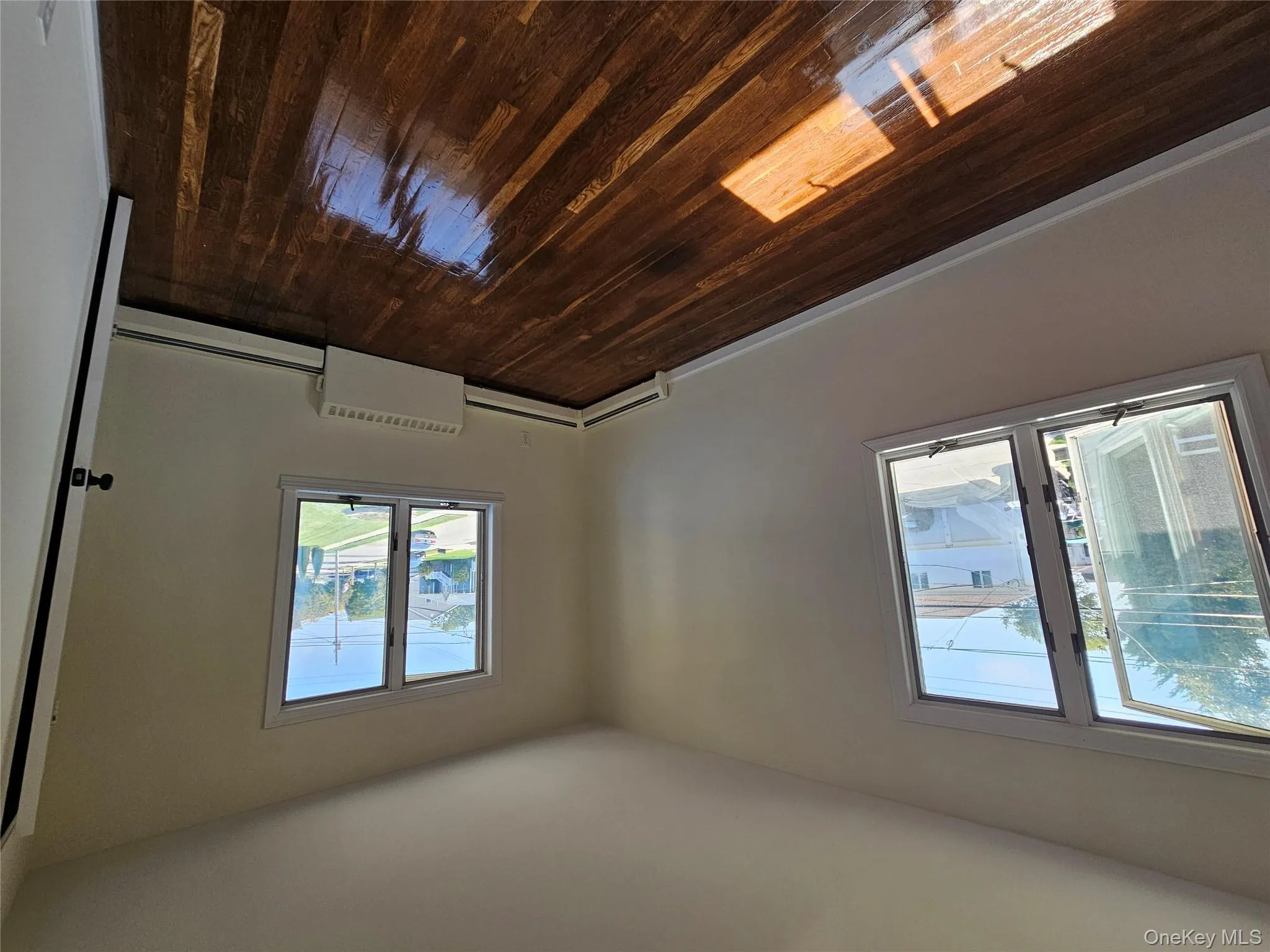 Empty room with dark wood-style flooring and a baseboard radiator Empty room with dark wood-style flooring and a baseboard radiator