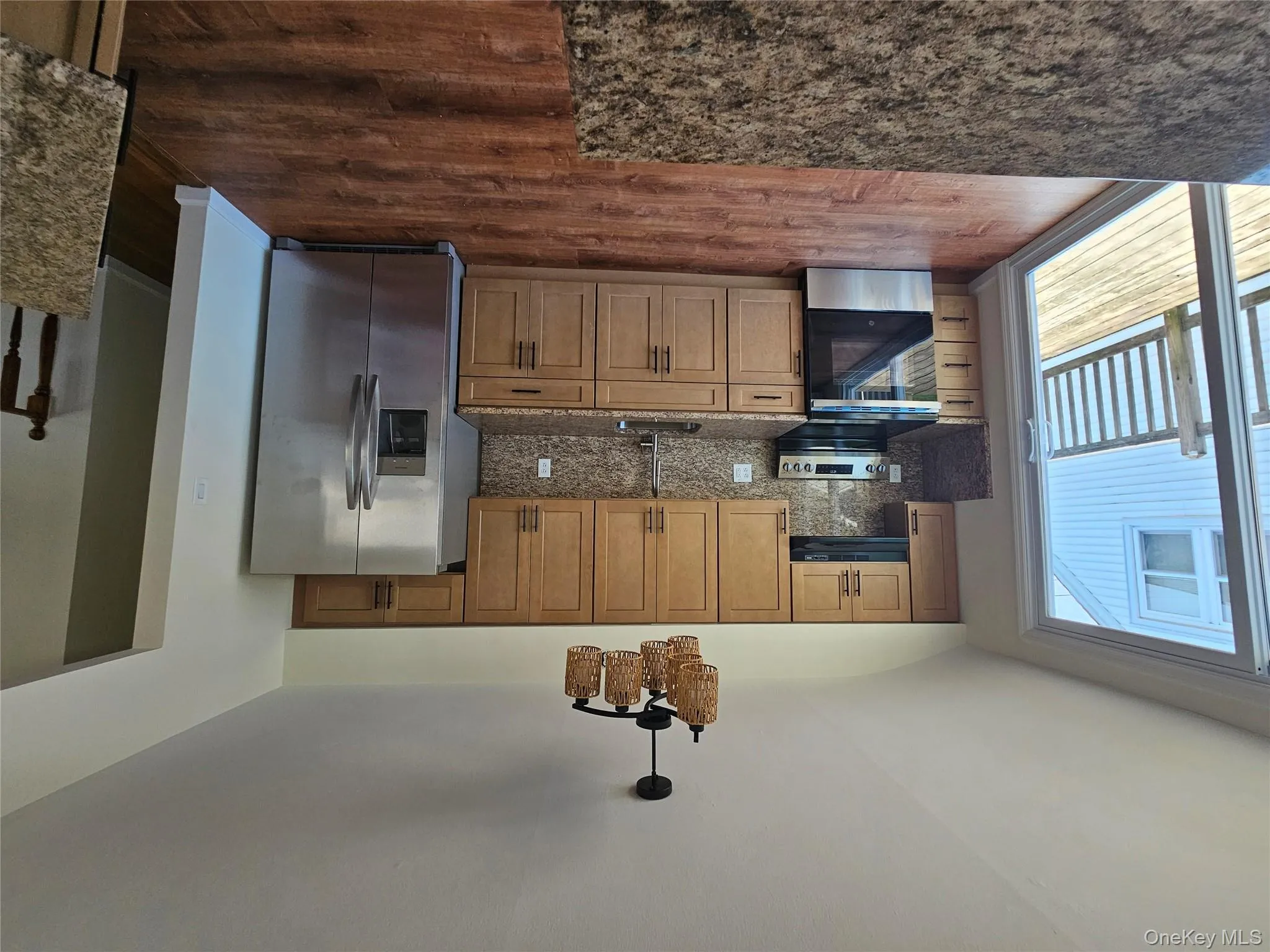 Kitchen with stainless steel appliances, dark stone countertops, dark wood finished floors, backsplash, and brown cabinets Kitchen with stainless steel appliances, dark stone countertops, dark wood finished floors, backsplash, and brown cabinets