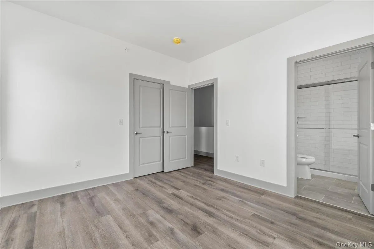 Unfurnished bedroom featuring light wood-style floors, ensuite bath, and a closet Unfurnished bedroom featuring light wood-style floors, ensuite bath, and a closet