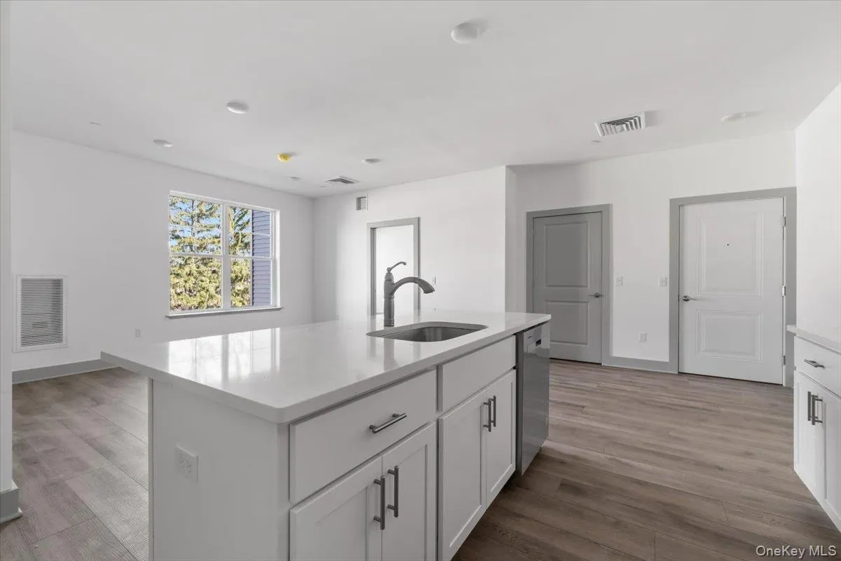 Kitchen with white cabinets, light stone countertops, a kitchen island with sink, and stainless steel dishwasher Kitchen with white cabinets, light stone countertops, a kitchen island with sink, and stainless steel dishwasher