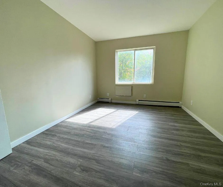 Spare room featuring dark wood-style flooring and baseboard heating Spare room featuring dark wood-style flooring and baseboard heating