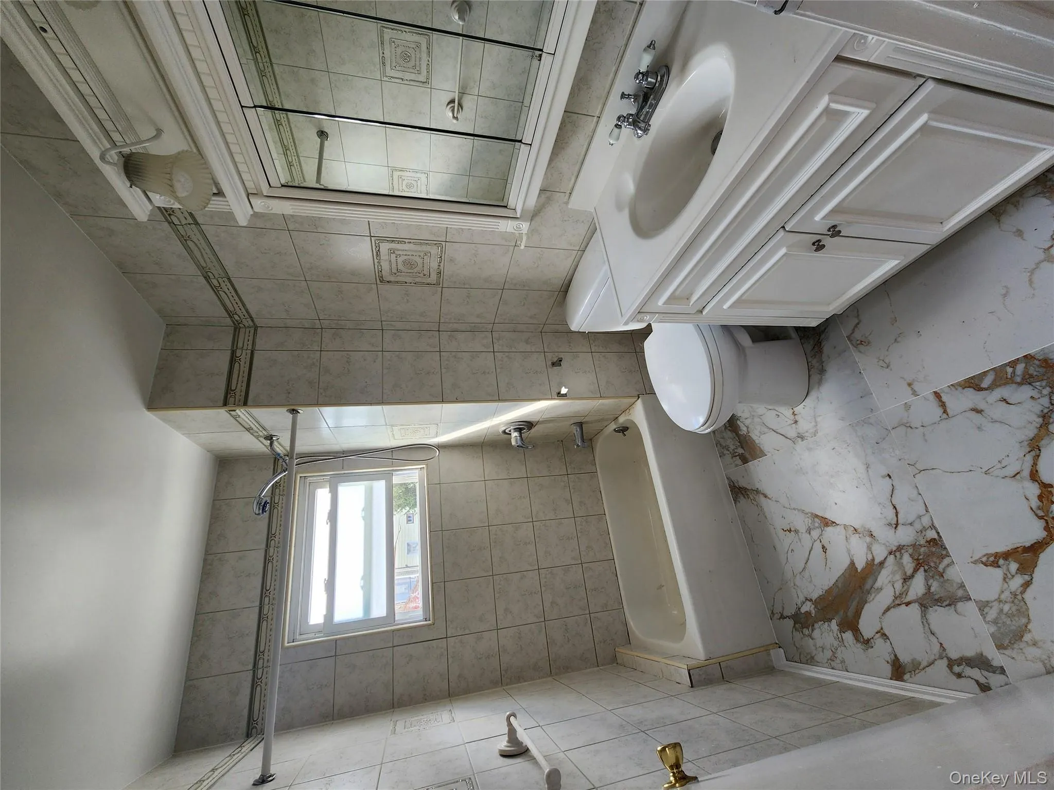Bathroom featuring tile walls, tub / shower combination, vanity, and light marble finish floors Bathroom featuring tile walls, tub / shower combination, vanity, and light marble finish floors