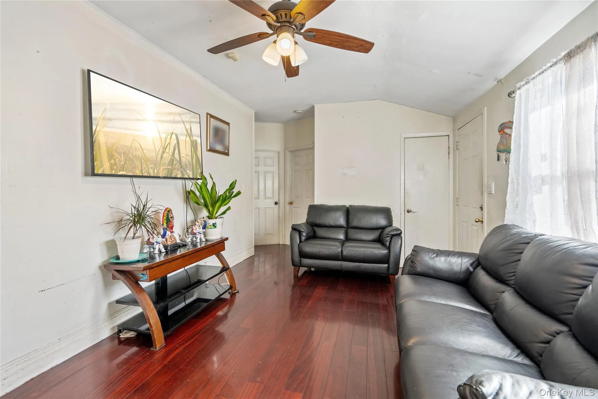Living room featuring dark wood finished floors, lofted ceiling, and ceiling fan Living room featuring dark wood finished floors, lofted ceiling, and ceiling fan