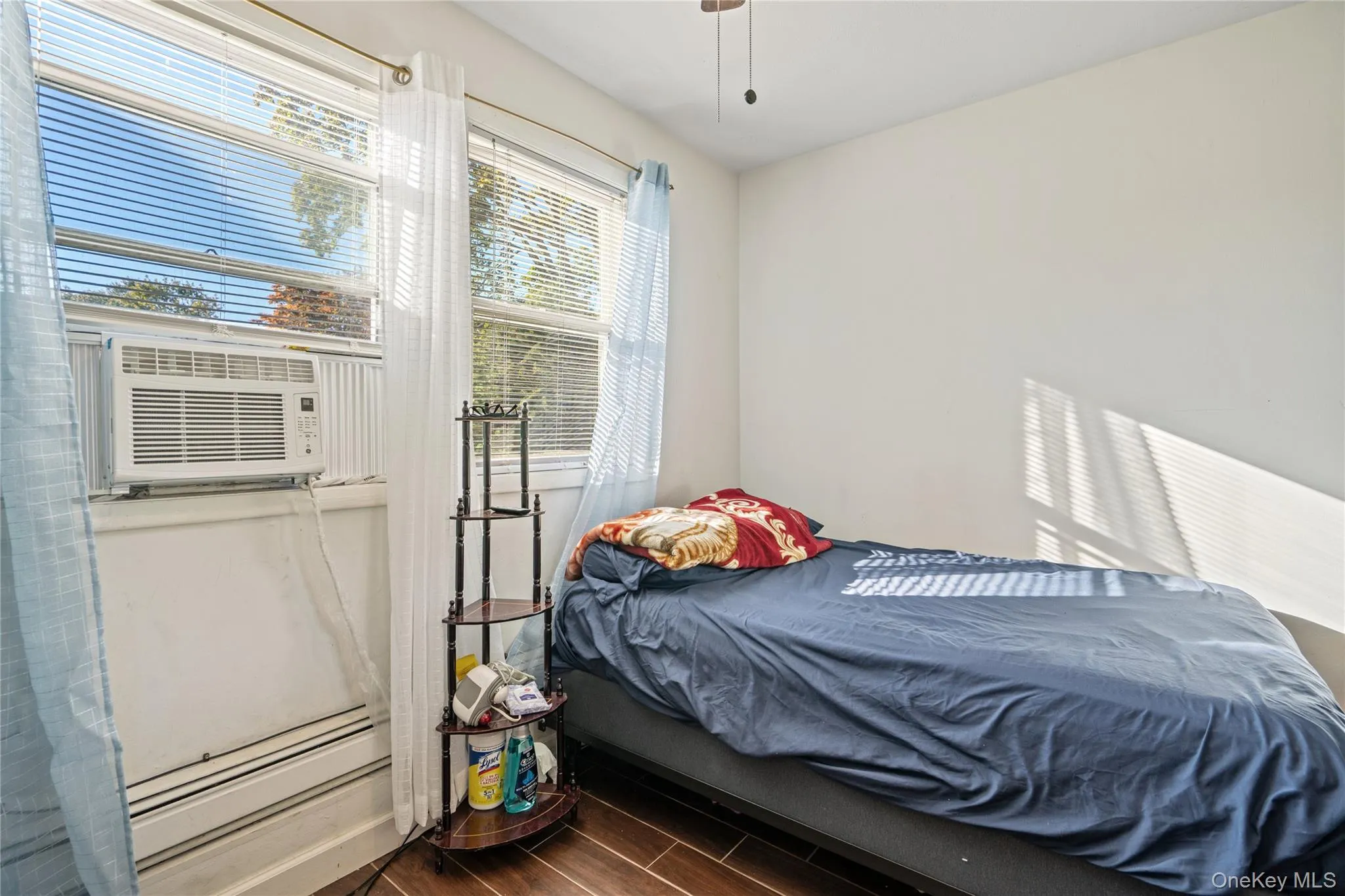 Bedroom with wood tiled floors, a baseboard heating unit, and cooling unit Bedroom with wood tiled floors, a baseboard heating unit, and cooling unit