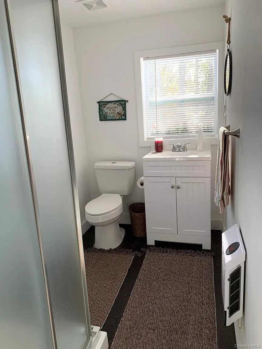 Bathroom featuring vanity, a stall shower, and heating unit Bathroom featuring vanity, a stall shower, and heating unit