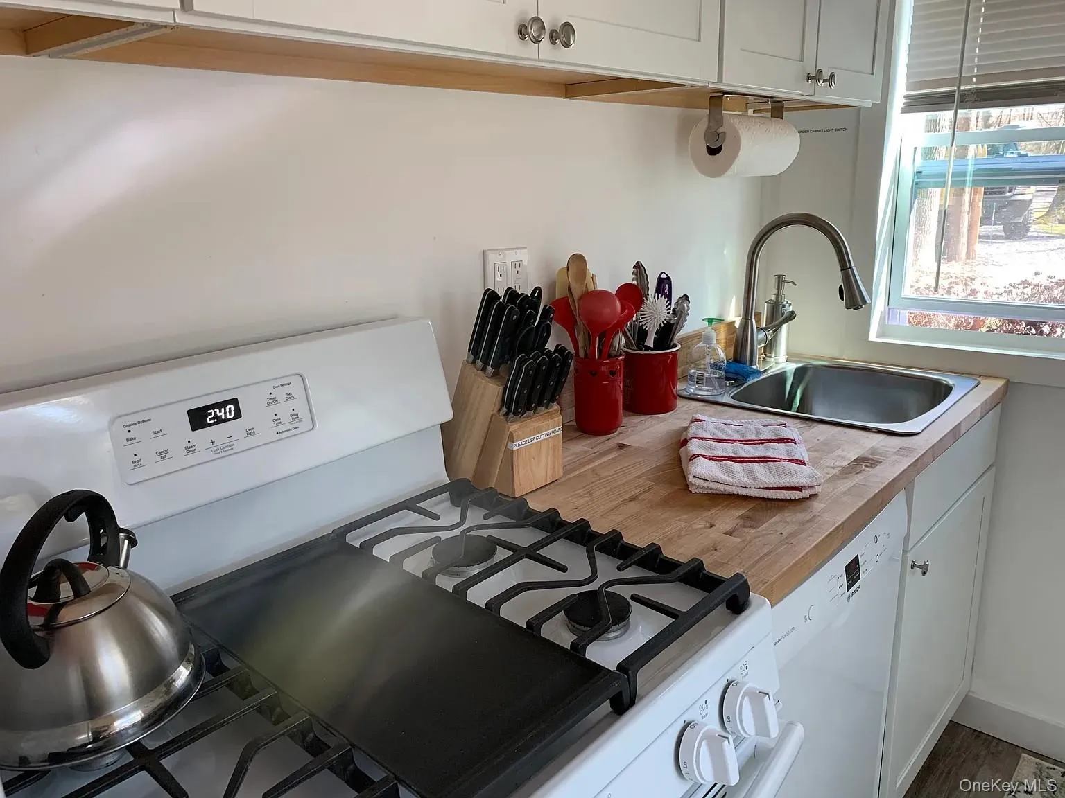 Kitchen featuring white cabinets, white appliances, and light countertops Kitchen featuring white cabinets, white appliances, and light countertops