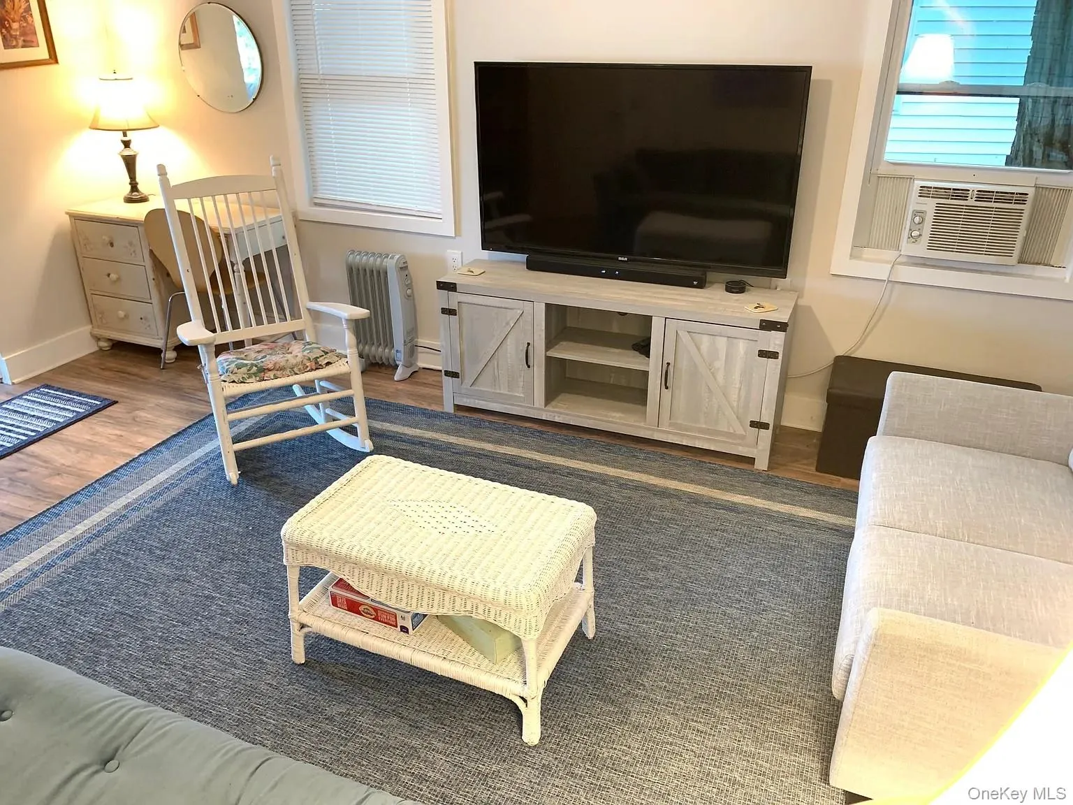 Living room with radiator heating unit, wood finished floors, and cooling unit Living room with radiator heating unit, wood finished floors, and cooling unit