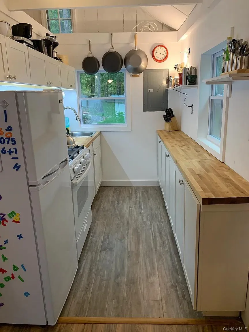 Kitchen featuring white cabinetry, wood counters, white appliances, open shelves, and electric panel Kitchen featuring white cabinetry, wood counters, white appliances, open shelves, and electric panel