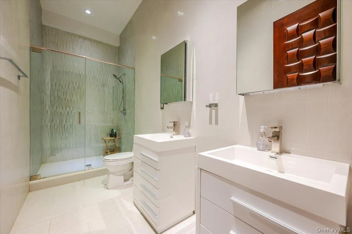 Full bathroom featuring a stall shower, two vanities, light tile patterned floors, and recessed lighting Full bathroom featuring a stall shower, two vanities, light tile patterned floors, and recessed lighting