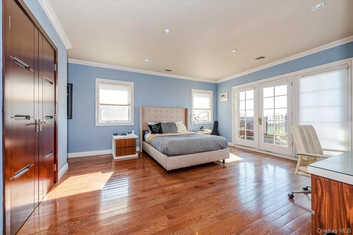 Bedroom with crown molding, access to outside, light wood-type flooring, a closet, and an office area Bedroom with crown molding, access to outside, light wood-type flooring, a closet, and an office area