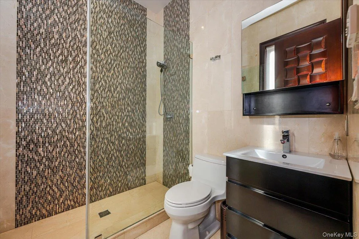 Bathroom with tile walls, vanity, and a shower stall Bathroom with tile walls, vanity, and a shower stall