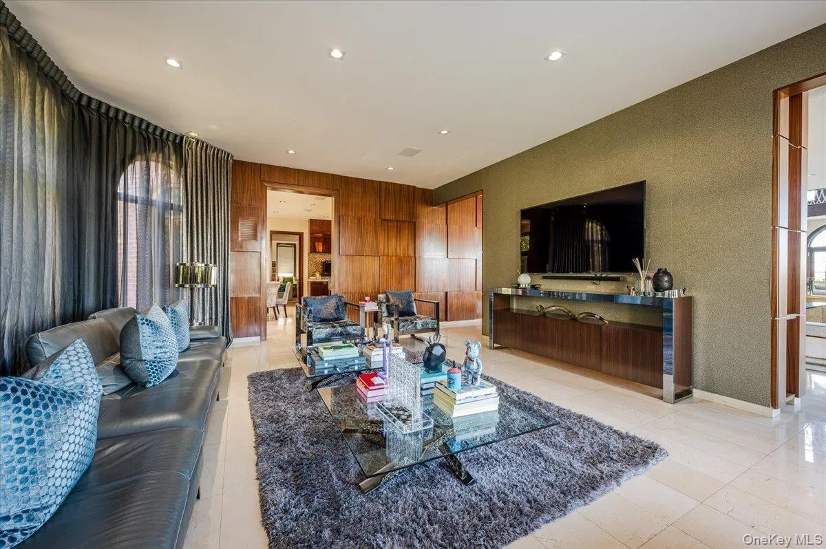 Living area featuring recessed lighting, light tile patterned flooring, and wooden walls Living area featuring recessed lighting, light tile patterned flooring, and wooden walls