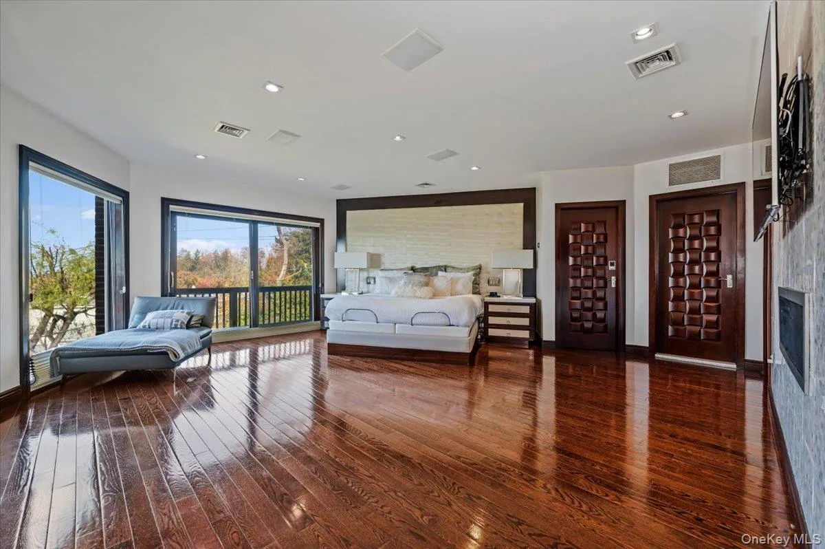 Bedroom featuring dark wood-type flooring, access to exterior, recessed lighting, and a fireplace Bedroom featuring dark wood-type flooring, access to exterior, recessed lighting, and a fireplace