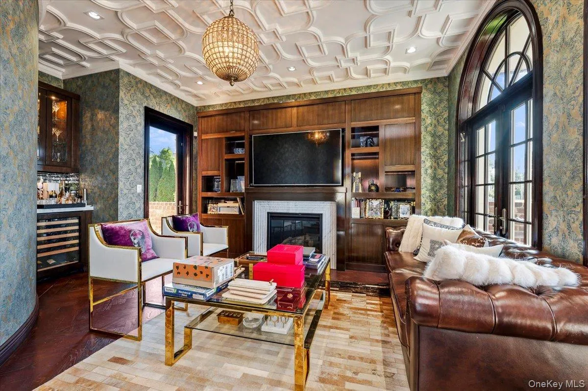 Living area with wallpapered walls, healthy amount of natural light, light wood-type flooring, wine cooler, and a glass covered fireplace Living area with wallpapered walls, healthy amount of natural light, light wood-type flooring, wine cooler, and a glass covered fireplace