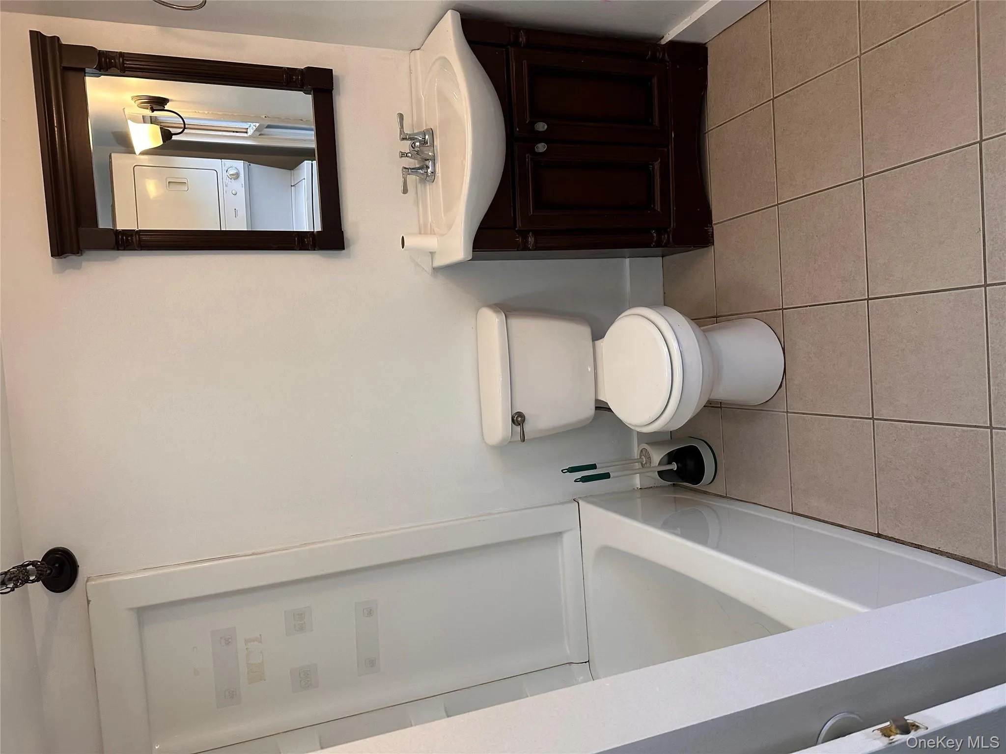 Full bathroom featuring vanity, light tile patterned floors, and estacked washer and dryer Full bathroom featuring vanity, light tile patterned floors, and estacked washer and dryer