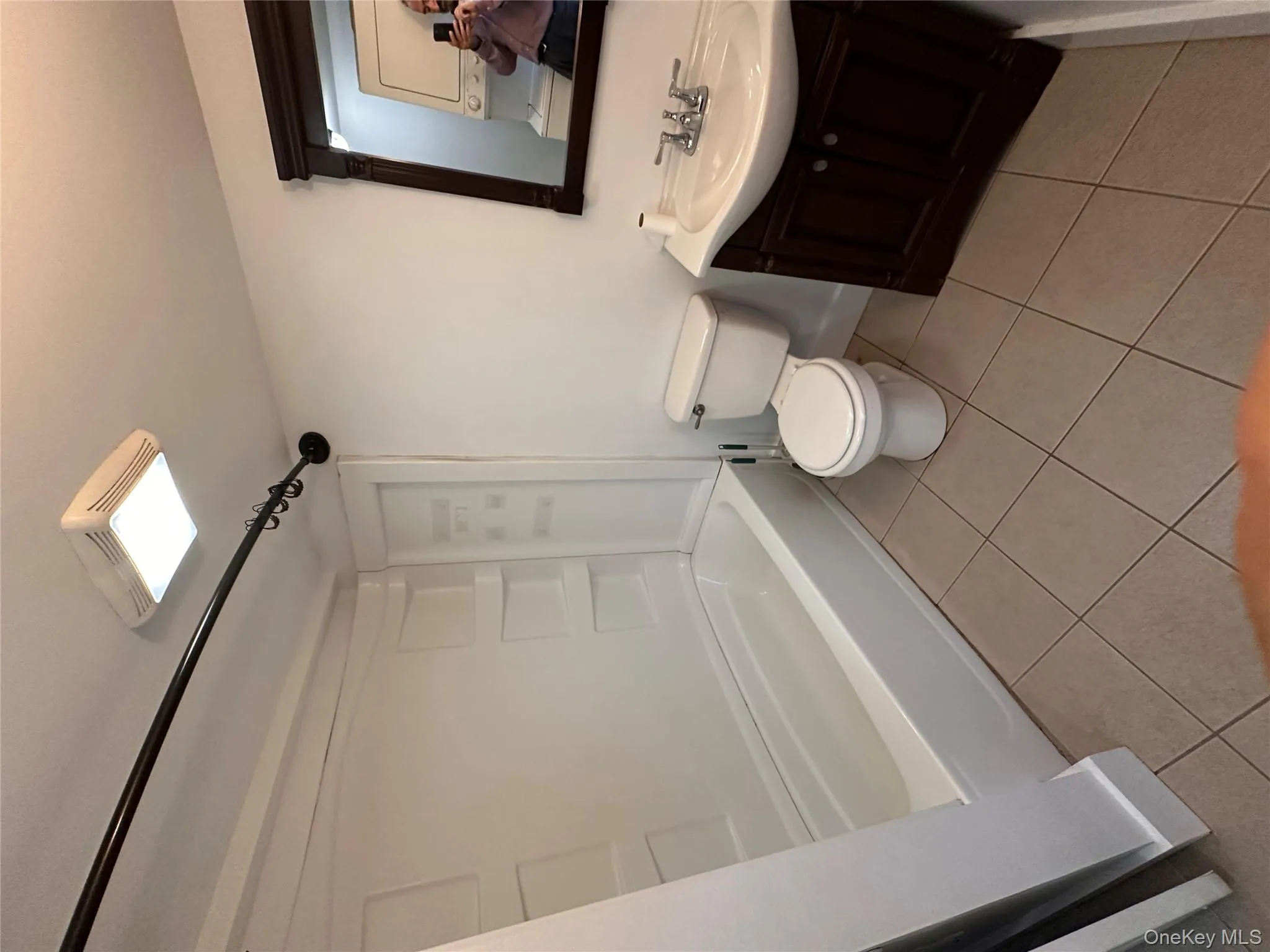 Bathroom featuring vanity, light tile patterned flooring, shower / tub combination, and stacked washer / dryer Bathroom featuring vanity, light tile patterned flooring, shower / tub combination, and stacked washer / dryer