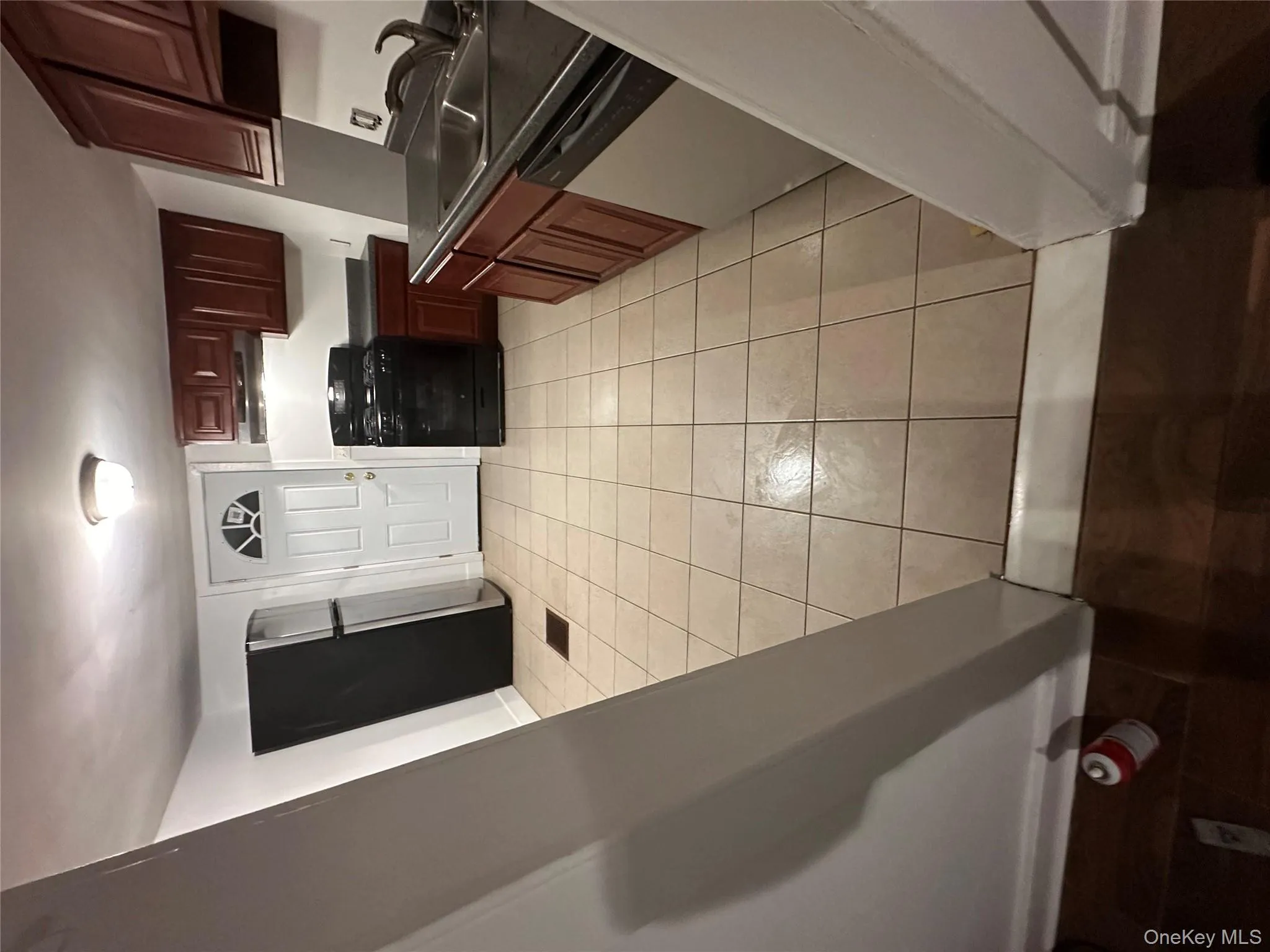 Kitchen featuring range, dark countertops, refrigerator, dishwashing machine, and light tile patterned floors Kitchen featuring range, dark countertops, refrigerator, dishwashing machine, and light tile patterned floors