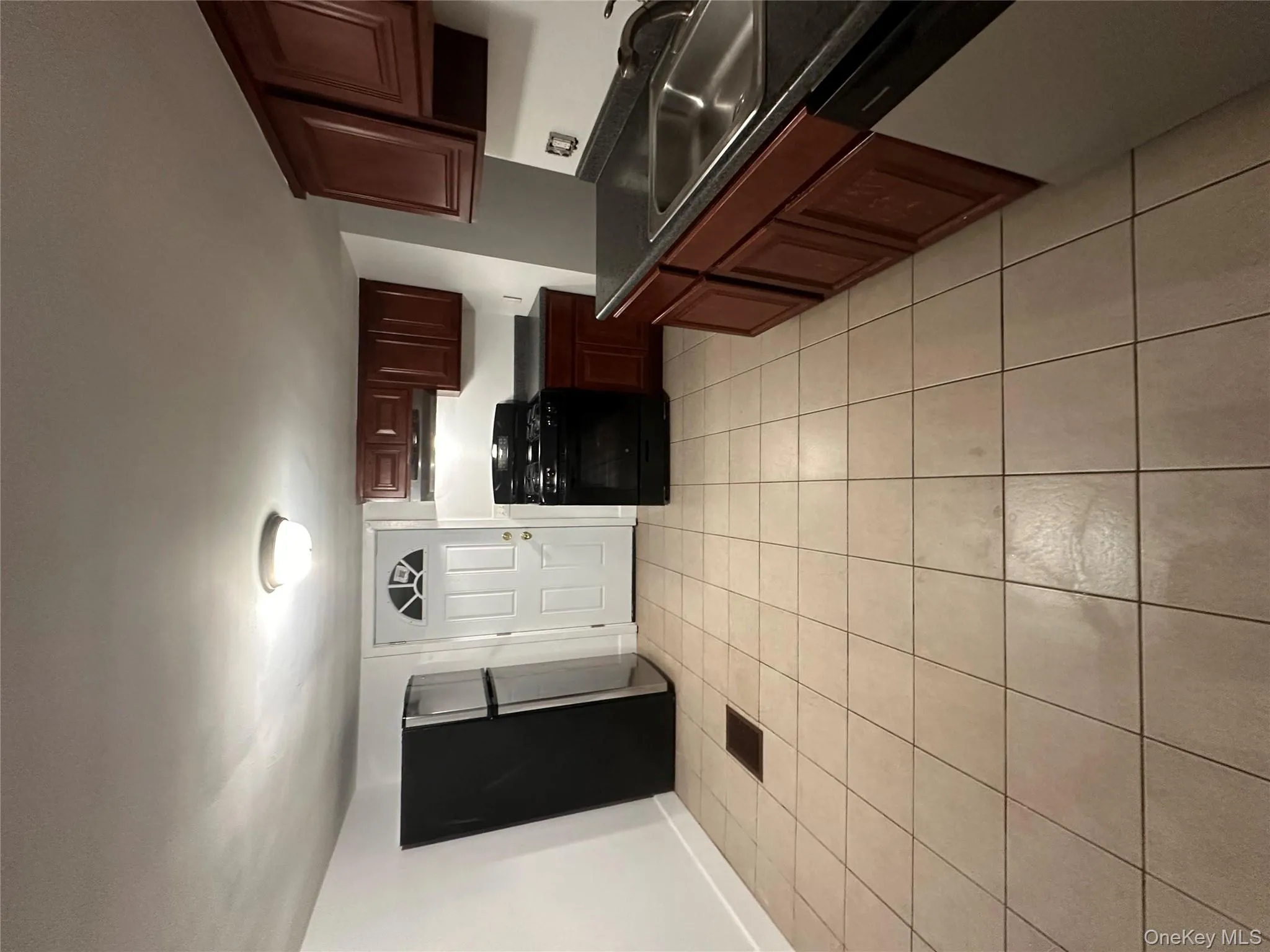 Kitchen with dark countertops, black range, fridge, dishwasher, and light tile patterned flooring Kitchen with dark countertops, black range, fridge, dishwasher, and light tile patterned flooring