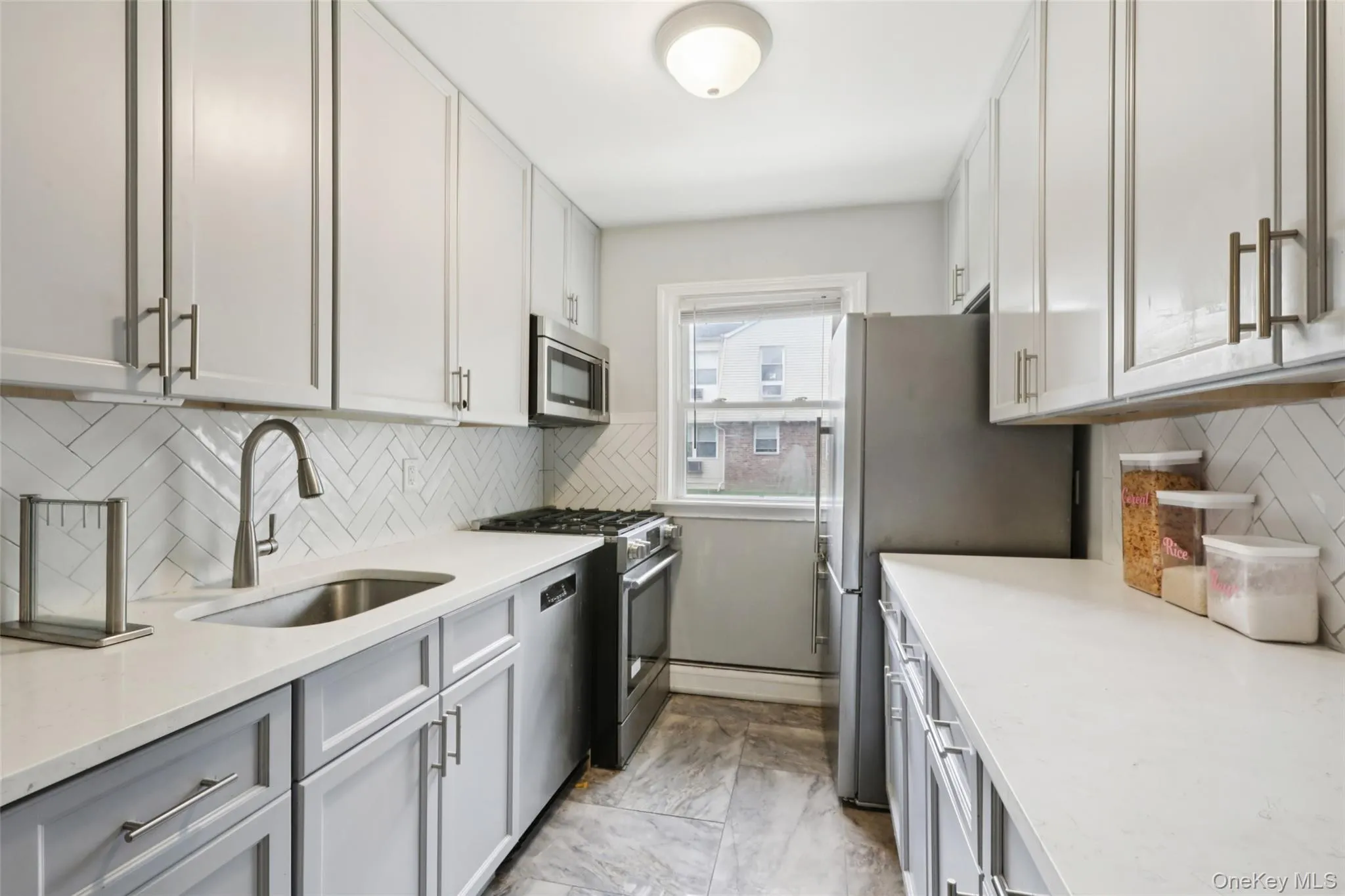 Kitchen with backsplash, stainless steel appliances, and light stone counters Kitchen with backsplash, stainless steel appliances, and light stone counters