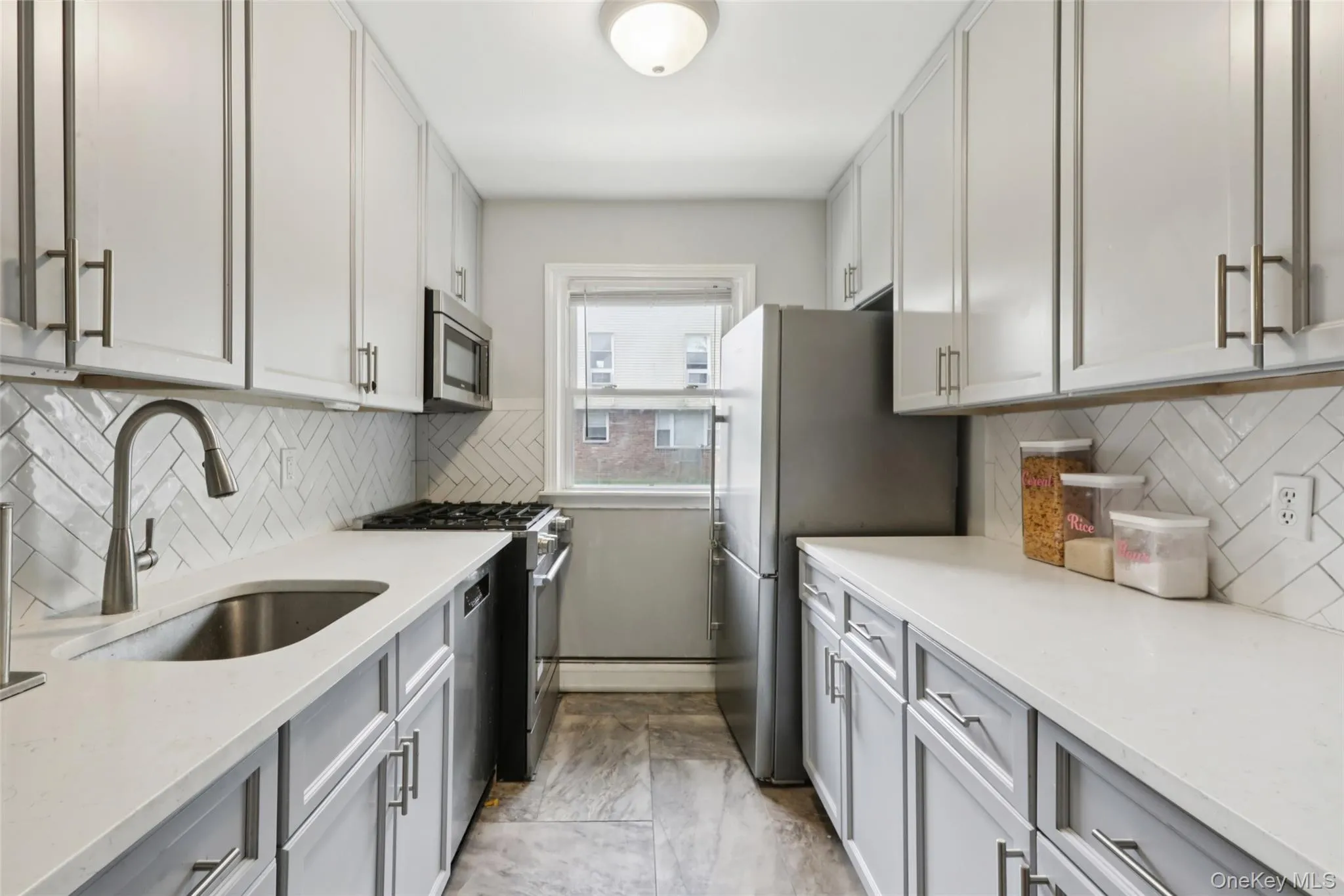 Kitchen featuring decorative backsplash, appliances with stainless steel finishes, light stone countertops, and white cabinets Kitchen featuring decorative backsplash, appliances with stainless steel finishes, light stone countertops, and white cabinets