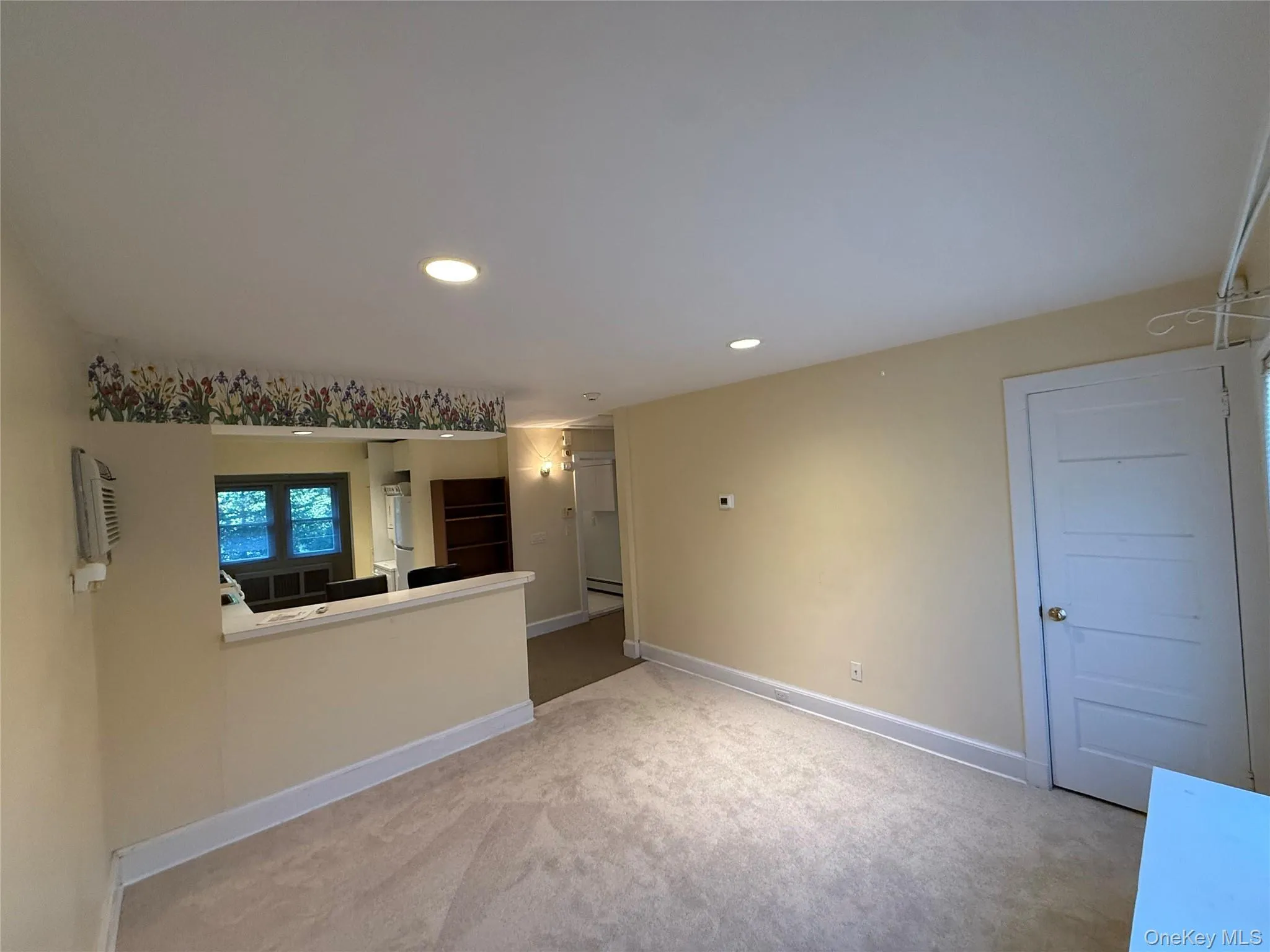 Unfurnished living room with recessed lighting, light colored carpet, and a baseboard radiator Unfurnished living room with recessed lighting, light colored carpet, and a baseboard radiator