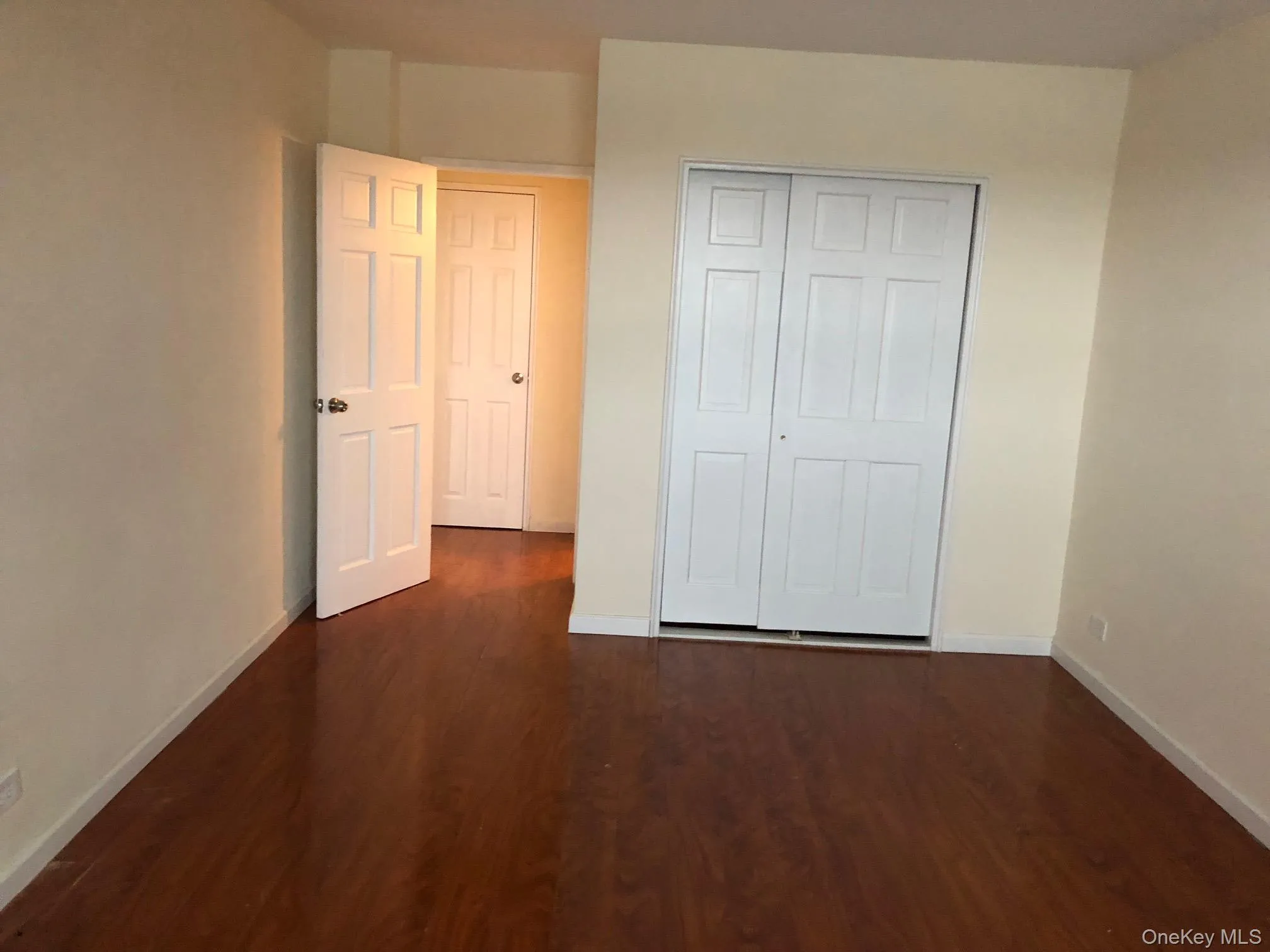 Unfurnished bedroom featuring dark wood-style flooring and a closet Unfurnished bedroom featuring dark wood-style flooring and a closet