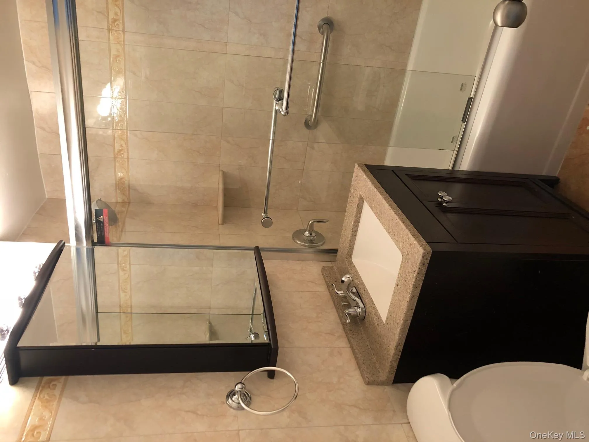 Bathroom with combined bath / shower with glass door, vanity, tile walls, and tile patterned flooring Bathroom with combined bath / shower with glass door, vanity, tile walls, and tile patterned flooring