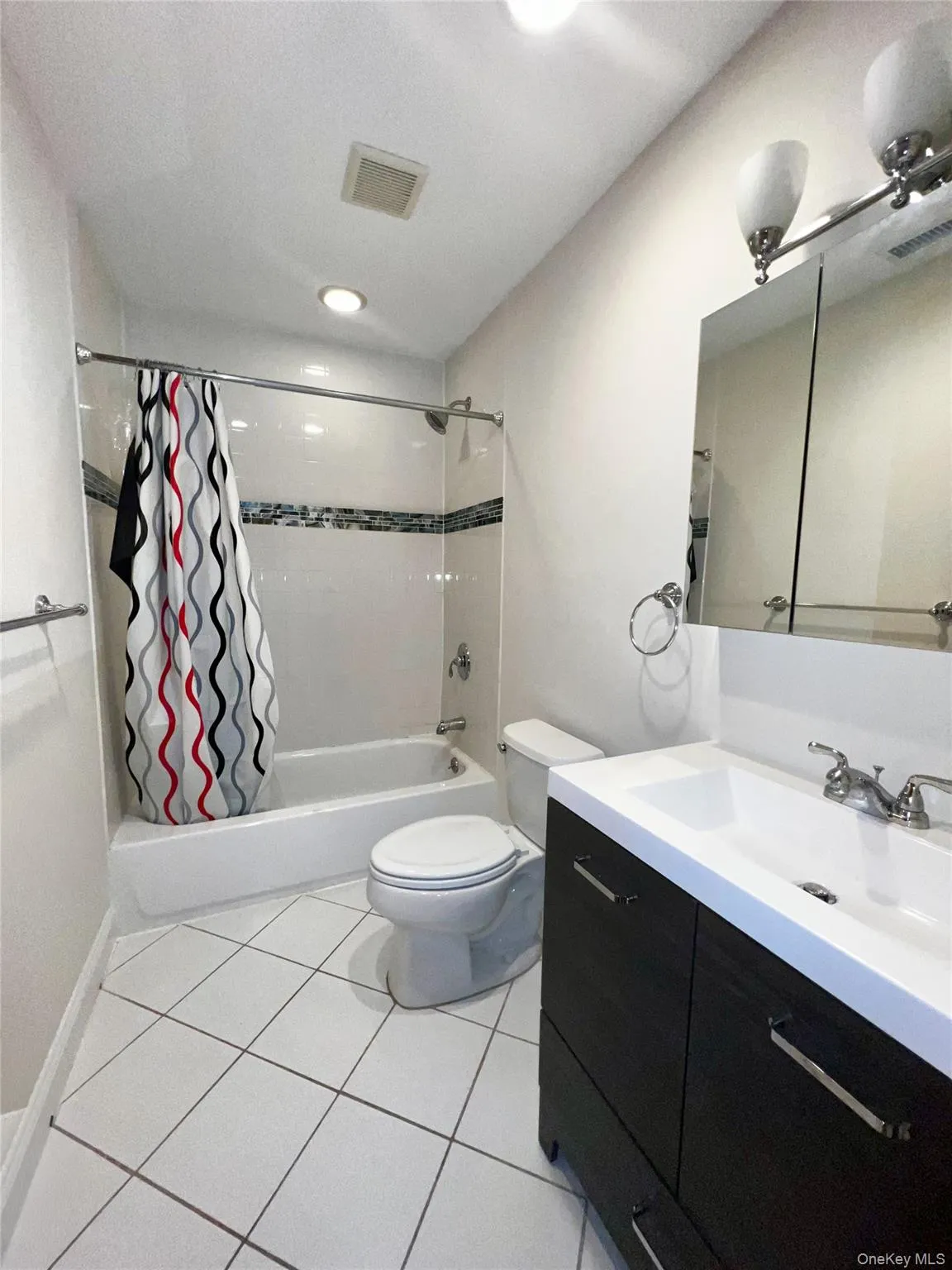 Full bathroom featuring shower / bath combo, light tile patterned floors, vanity, and a textured ceiling Full bathroom featuring shower / bath combo, light tile patterned floors, vanity, and a textured ceiling