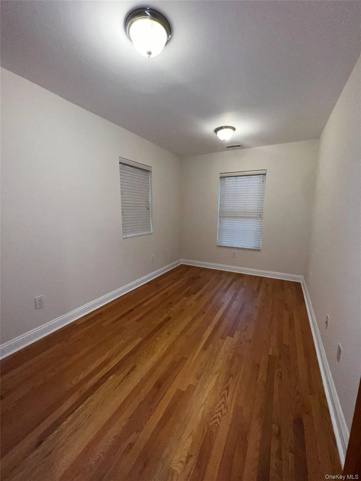 Spare room with baseboards and light wood-type flooring Spare room with baseboards and light wood-type flooring