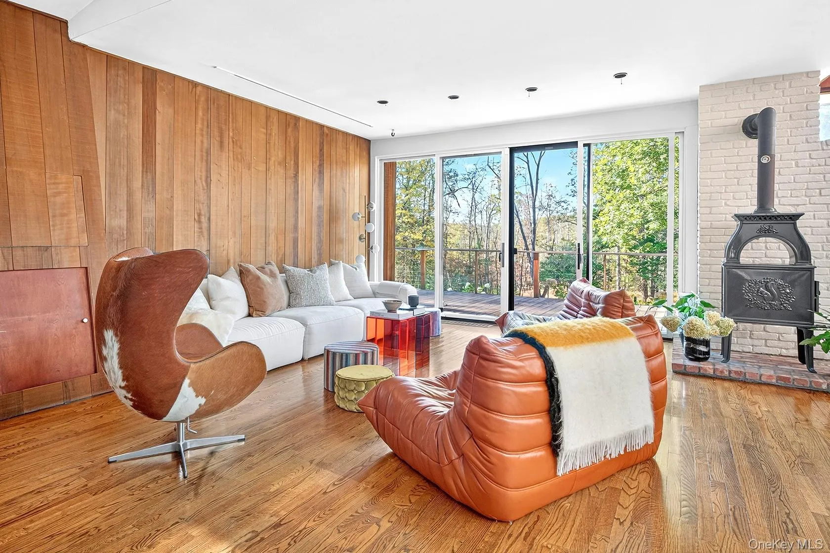 Living room with a wood stove, light wood finished floors, and wood walls Living room with a wood stove, light wood finished floors, and wood walls