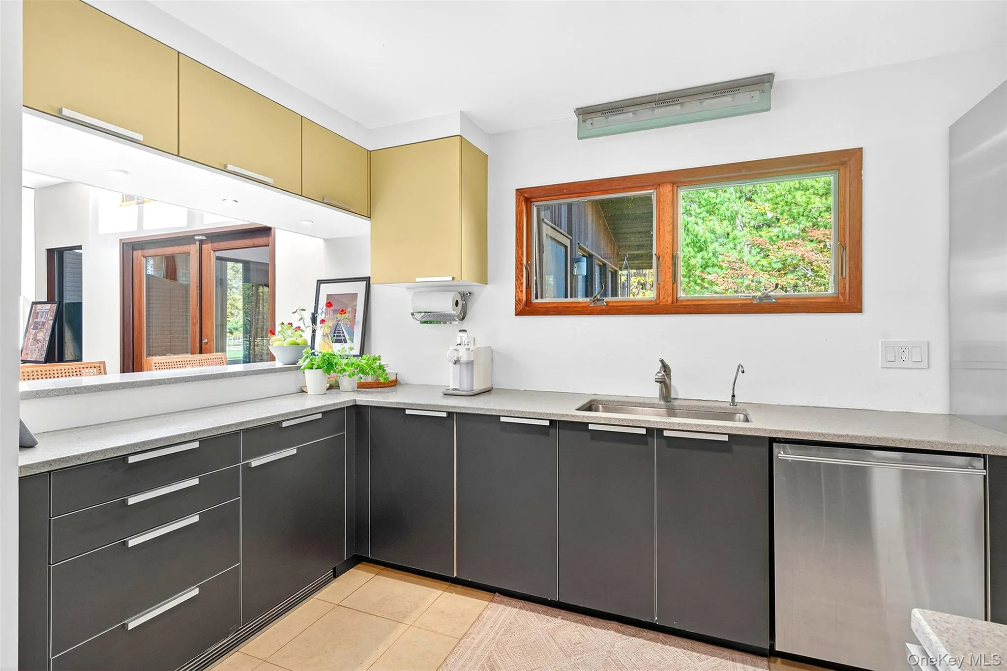 Kitchen featuring dishwasher, plenty of natural light, light tile patterned floors, and modern cabinets Kitchen featuring dishwasher, plenty of natural light, light tile patterned floors, and modern cabinets