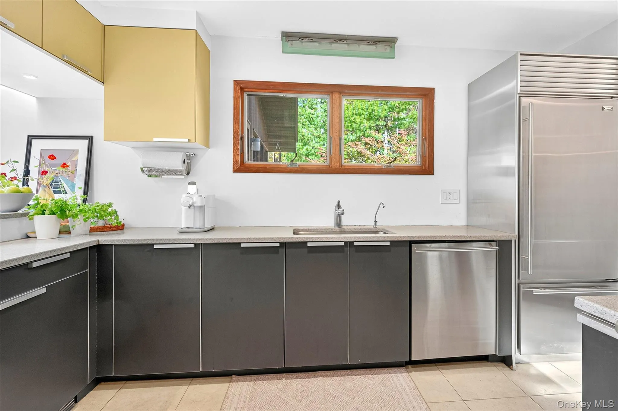 Kitchen with stainless steel appliances, light tile patterned floors, light stone countertops, and modern cabinets Kitchen with stainless steel appliances, light tile patterned floors, light stone countertops, and modern cabinets