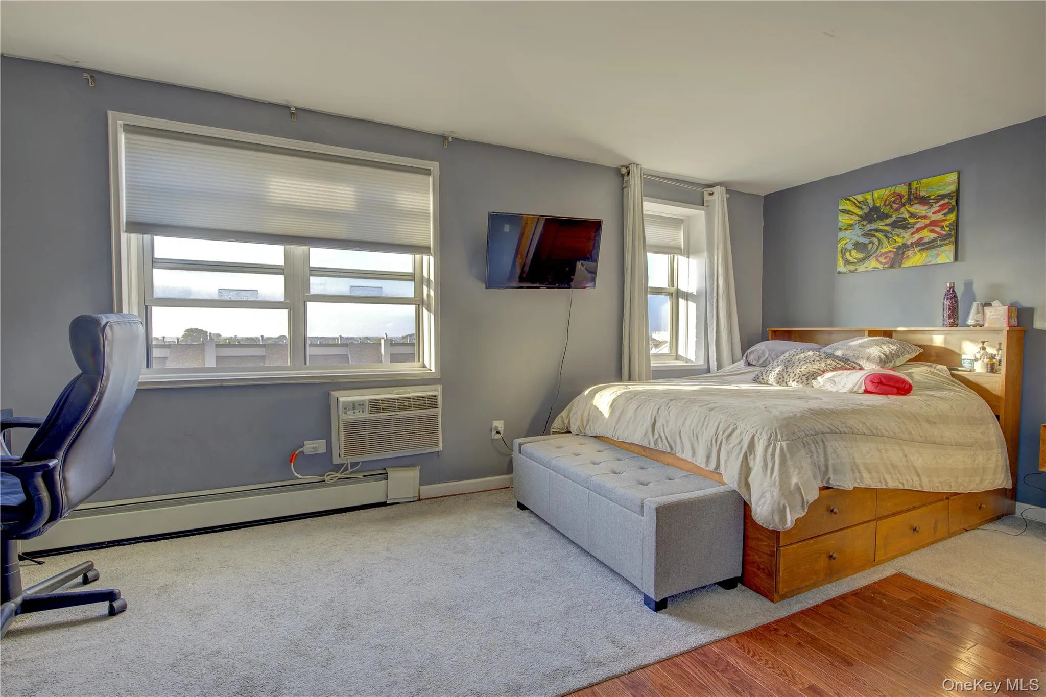 Bedroom with baseboard heating, wood finished floors, and a wall mounted AC Bedroom with baseboard heating, wood finished floors, and a wall mounted AC