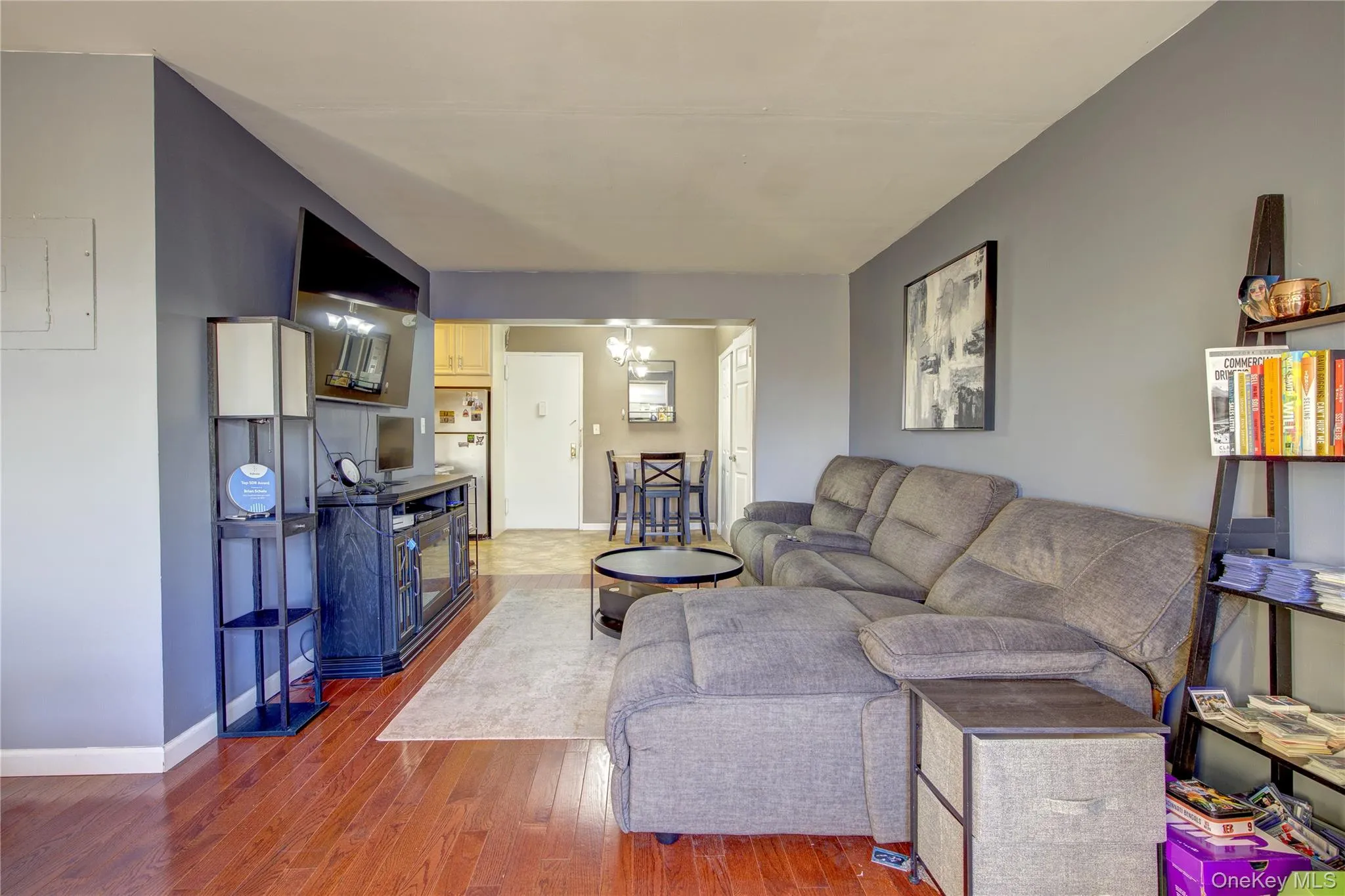Living area with hardwood / wood-style floors, a chandelier, and electric panel Living area with hardwood / wood-style floors, a chandelier, and electric panel