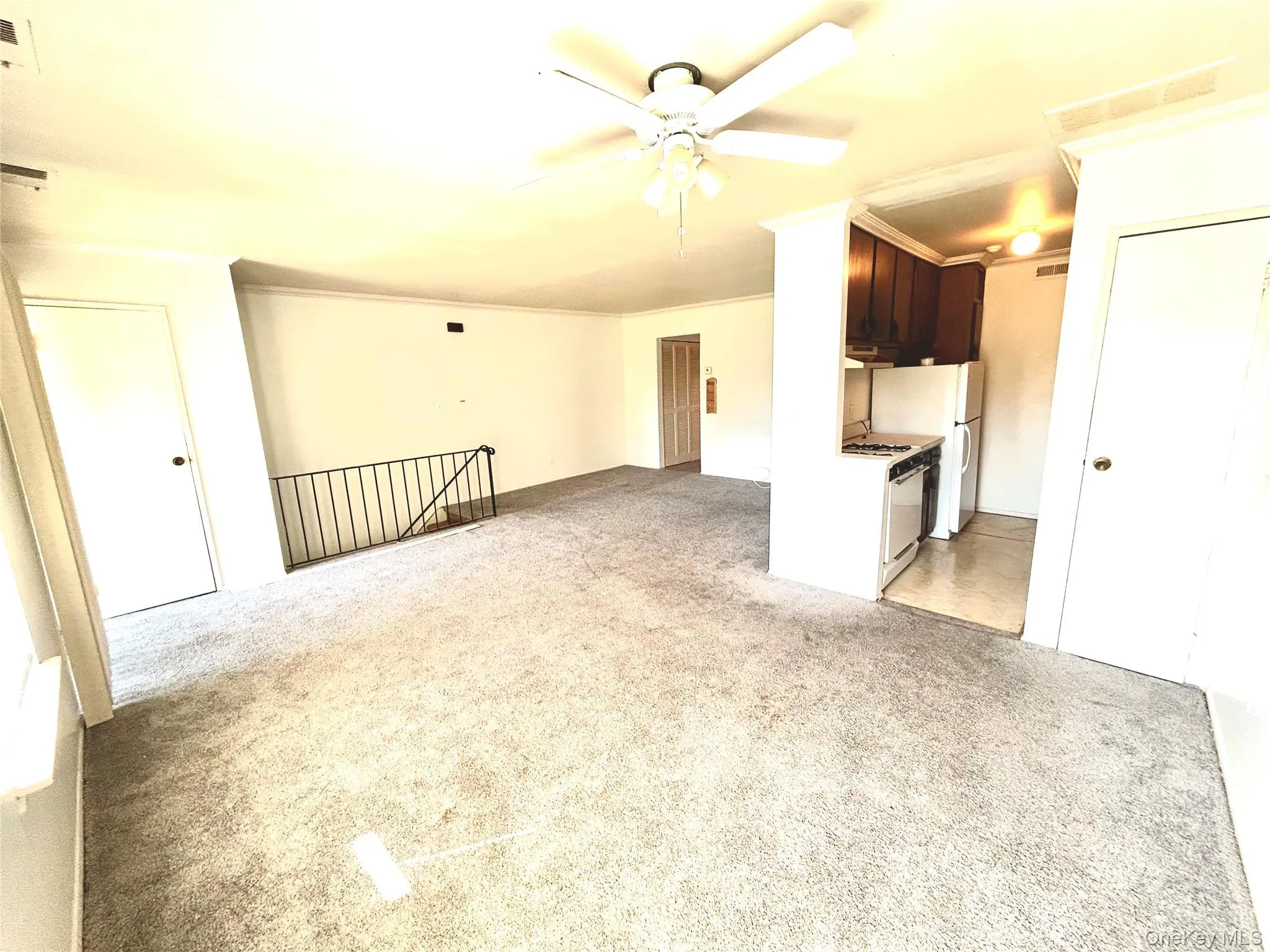 Unfurnished living room featuring light carpet, ceiling fan, and crown molding Unfurnished living room featuring light carpet, ceiling fan, and crown molding