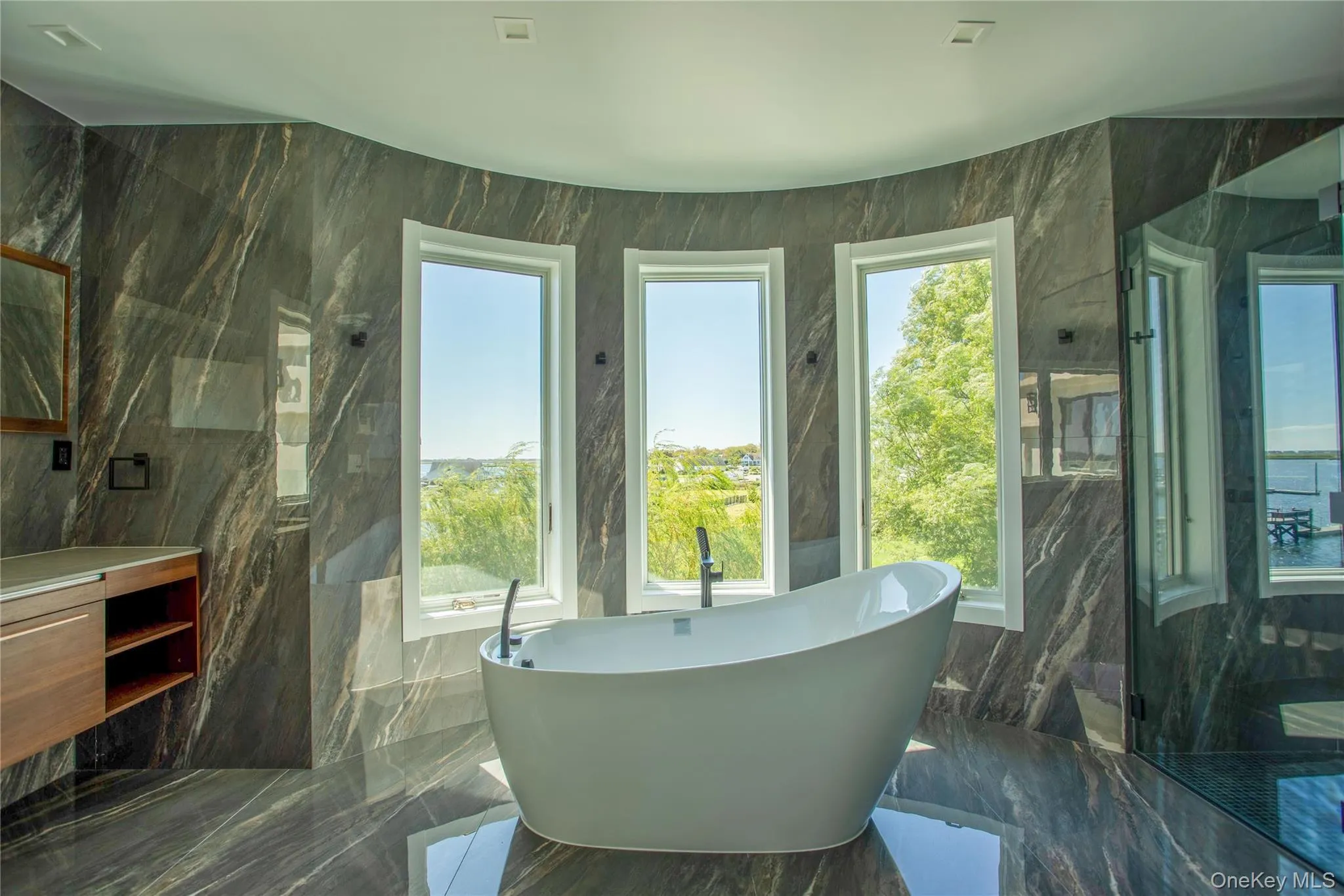 Bathroom with tile walls, a freestanding tub, dark marble finish floors, a marble finish shower, and vanity Bathroom with tile walls, a freestanding tub, dark marble finish floors, a marble finish shower, and vanity