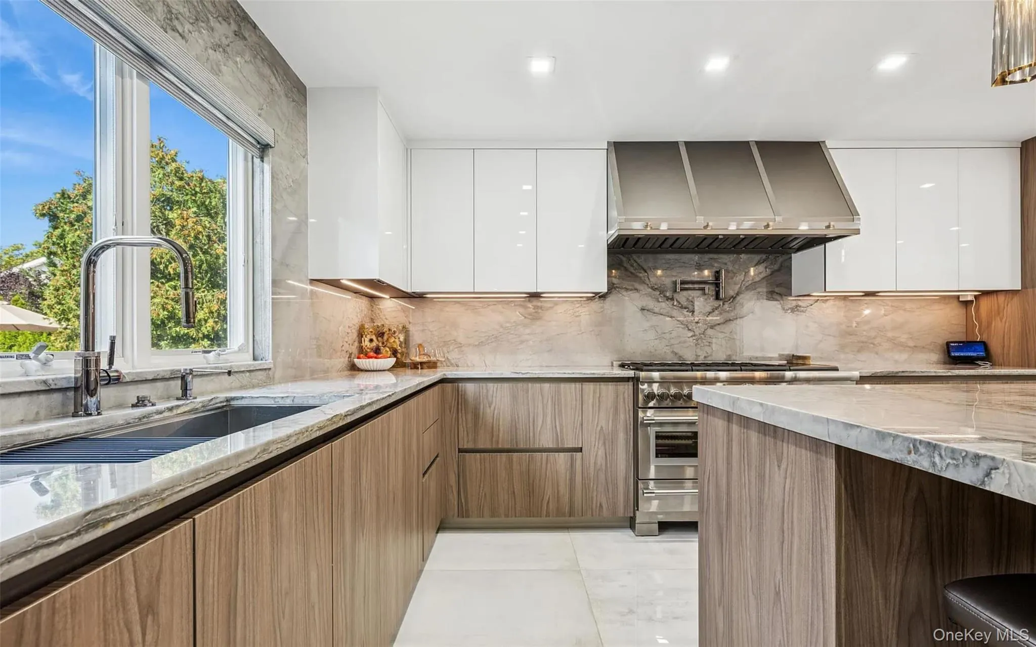 Kitchen featuring light stone counters, modern cabinets, stainless steel range, wall chimney exhaust hood, and recessed lighting Kitchen featuring light stone counters, modern cabinets, stainless steel range, wall chimney exhaust hood, and recessed lighting