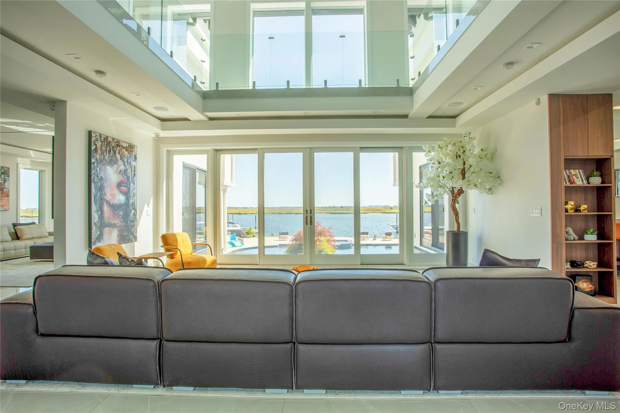 Living area with a water view, tile patterned floors, a towering ceiling, and a tray ceiling Living area with a water view, tile patterned floors, a towering ceiling, and a tray ceiling