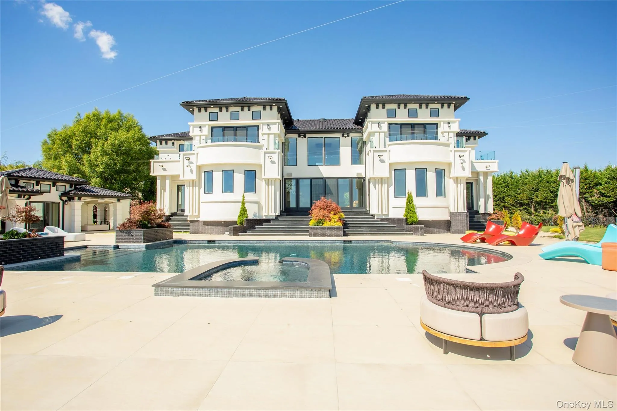 Rear view of property with a patio, stucco siding, and a pool with connected hot tub Rear view of property with a patio, stucco siding, and a pool with connected hot tub