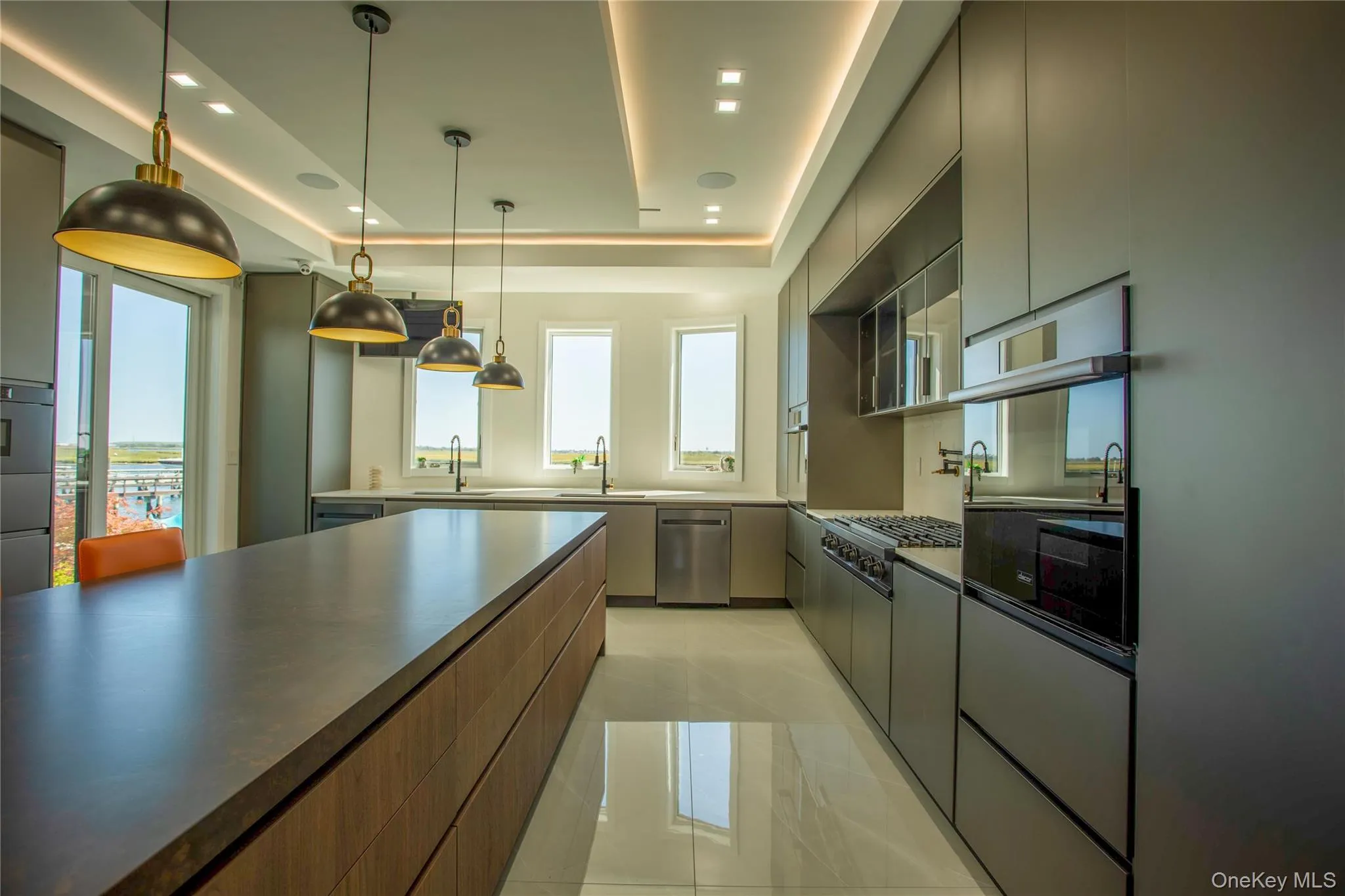 Kitchen featuring modern cabinets, a tray ceiling, decorative light fixtures, stainless steel appliances, and recessed lighting Kitchen featuring modern cabinets, a tray ceiling, decorative light fixtures, stainless steel appliances, and recessed lighting