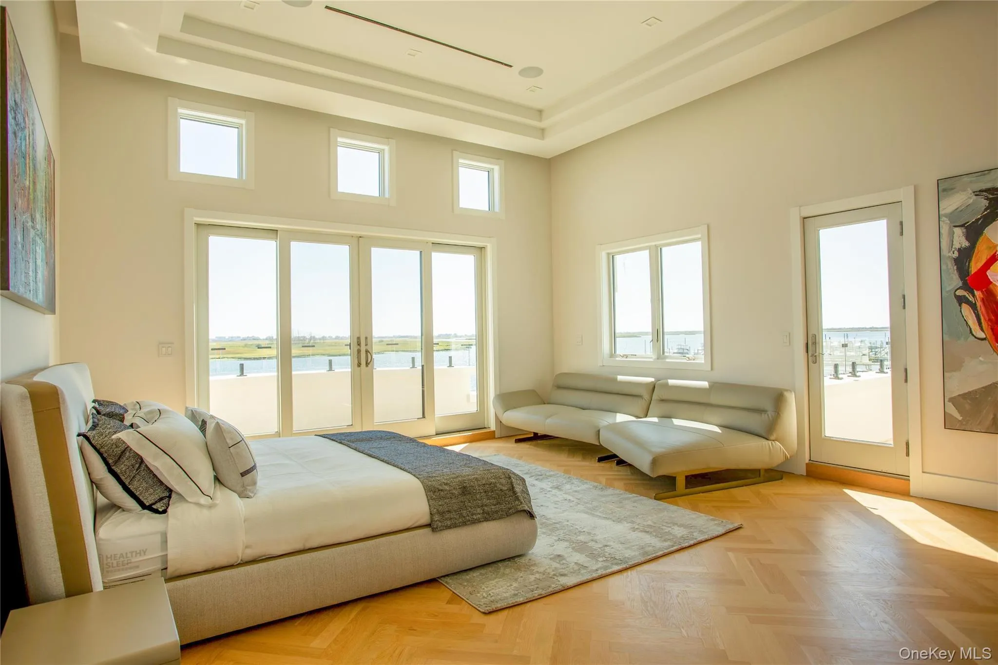 Living room featuring plenty of natural light, a water view, a tray ceiling, and a high ceiling Living room featuring plenty of natural light, a water view, a tray ceiling, and a high ceiling
