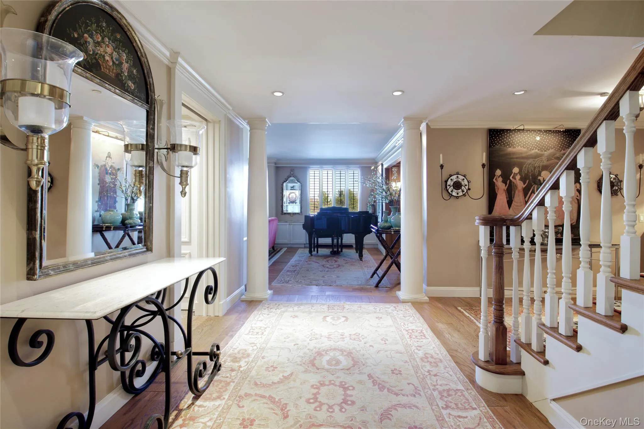 Hallway with light wood-style flooring, crown molding, recessed lighting, ornate columns, and stairway Hallway with light wood-style flooring, crown molding, recessed lighting, ornate columns, and stairway