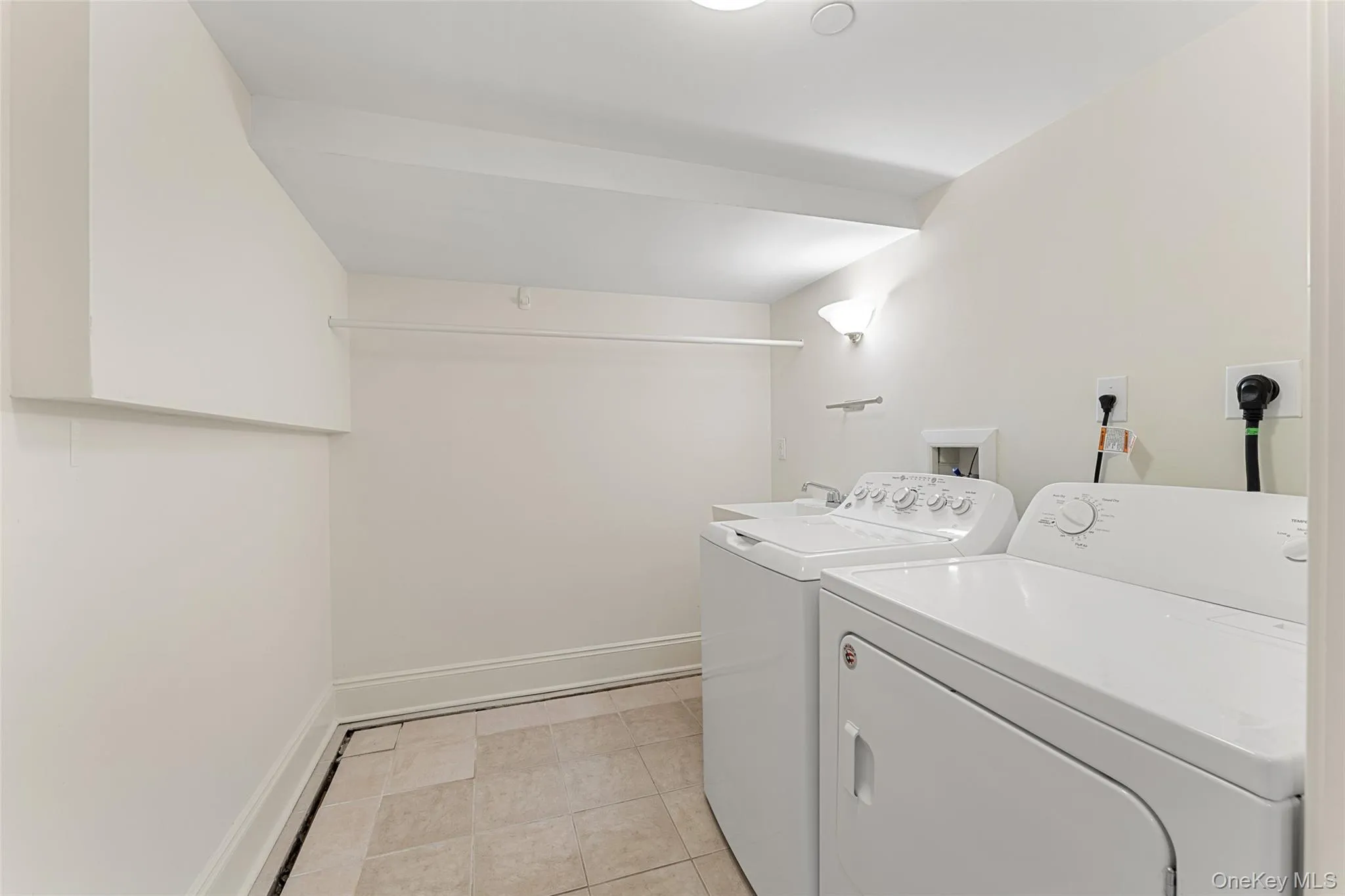 Laundry room with independent washer and dryer and light tile patterned floors Laundry room with independent washer and dryer and light tile patterned floors